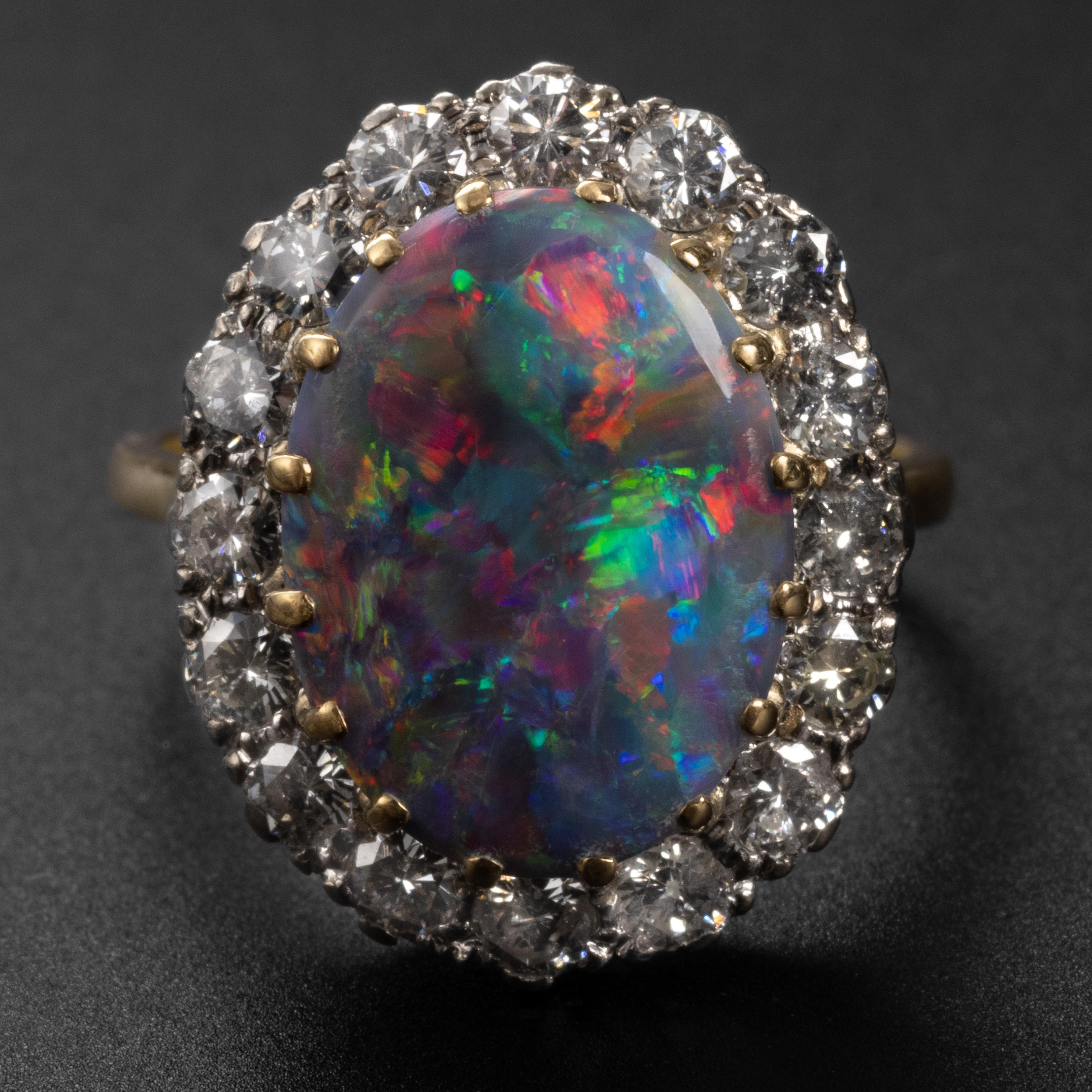 A spectacular certified untreated Australian black opal is the dazzling centerpiece of this English Mid-century ring. The magnificent solid black opal bursts with a kaleidoscope of color: vivid red, orange, yellow, pink, blue & green, displaying the