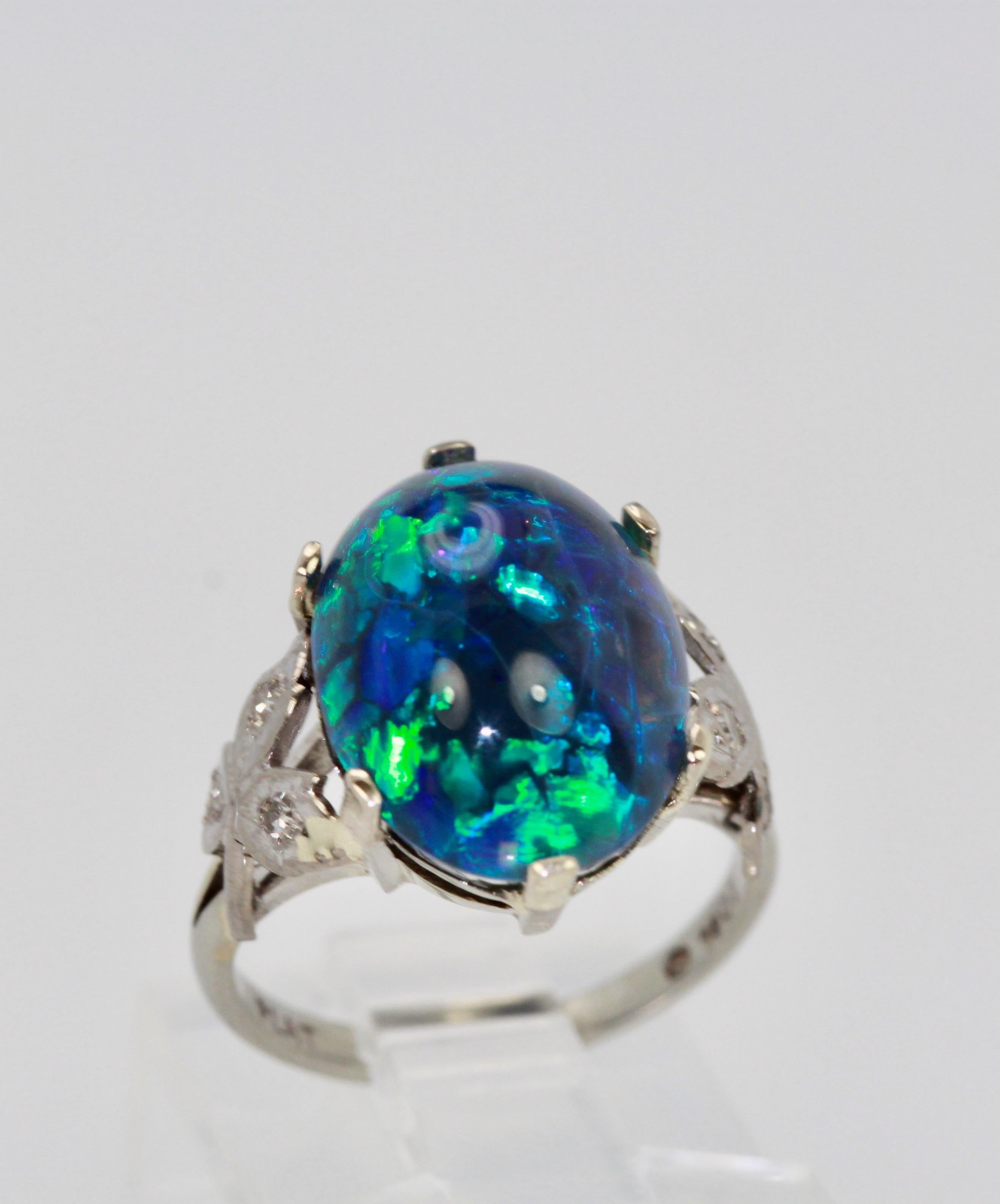 This black Opal Platinum ring is set with 3 small Diamonds on each of the sides with a leaf design.  The Opal measures 14.3 x 10.72 with a depth of 6.02. It is oval with a lovely Matrix of deep blues a bit if green and ever so slight red.  Currently