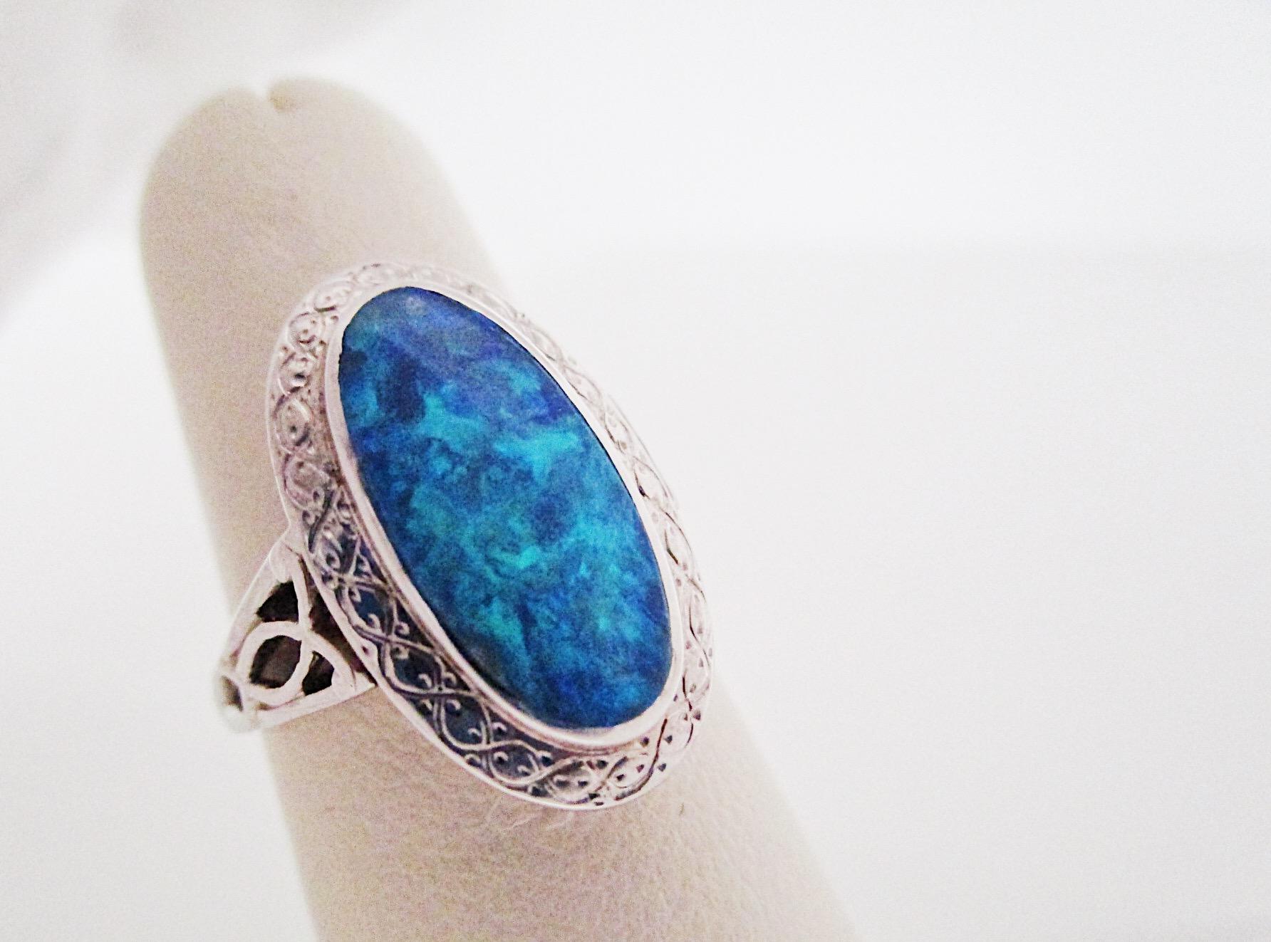 This is an excellent example of Black Opal set in 14K white gold. There is lovely scroll-work around the bezel that will protect the opal from damage. October babies will love the vibrant blue with green flashes, actually anyone would love