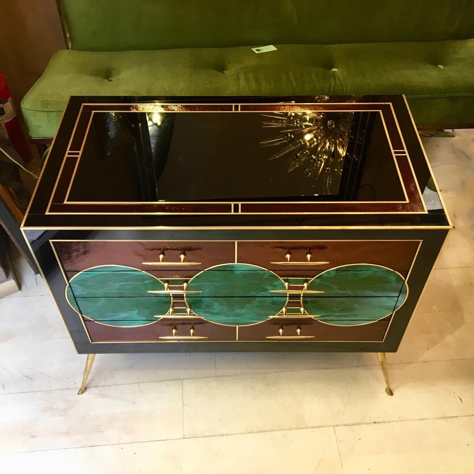 Opaline glass chest of drawers, frontal decoration with green opaline glass circles malachite effect, black and plum color opaline glass top and sides, brass inlays, handels and legs, three drawers.