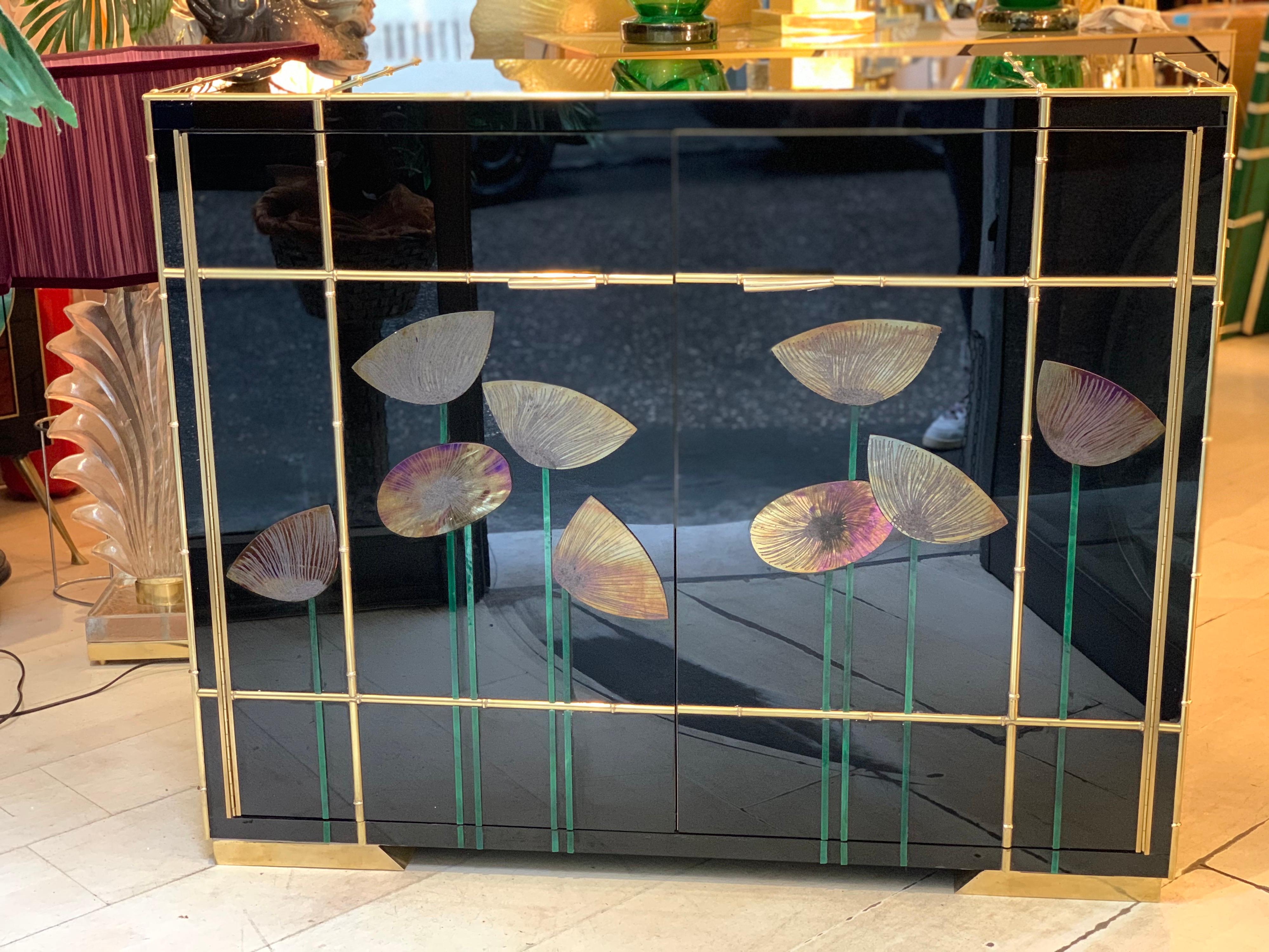Black Opaline glass credenza decorated with mirrored Iridescent glass poppies, brass bamboo frames and inlays.
The credenza has two doors and shelves inside, brass legs and handles. It is a unique and highly decorative piece.
 
 