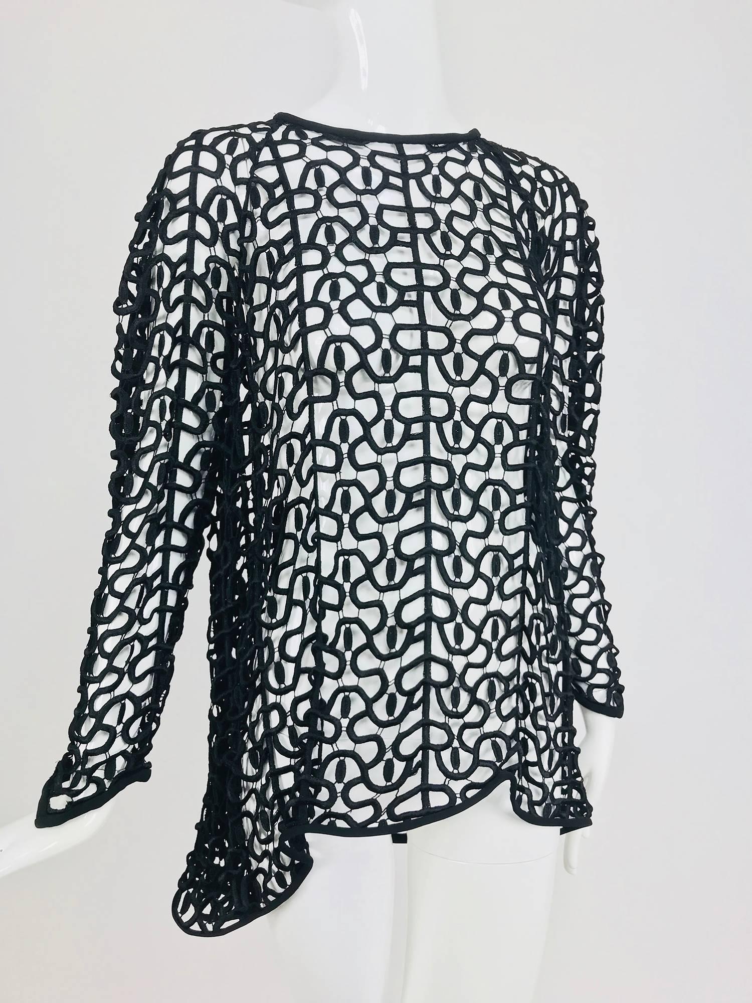 Black open work embroidered top with high low hem...Made like cut work lace of heavily embroidered thread with delicate connector threads facings of black crepe...Well made pull on top has long raglan sleeves that each end in points at the cuffs,