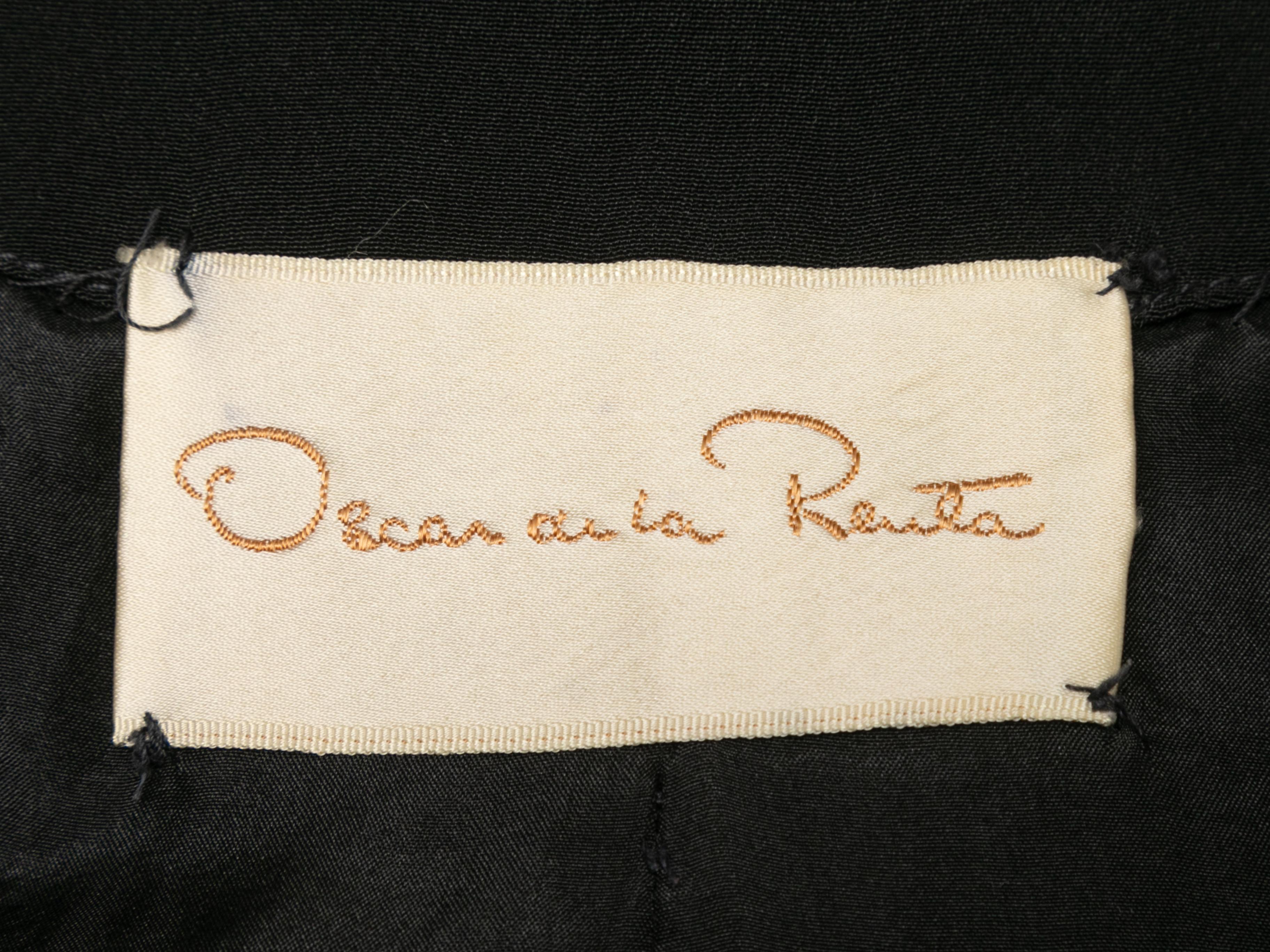Black short sleeve dress by Oscar de la Renta. Ruffle trim. V-neck. Zip closure at center front. 32