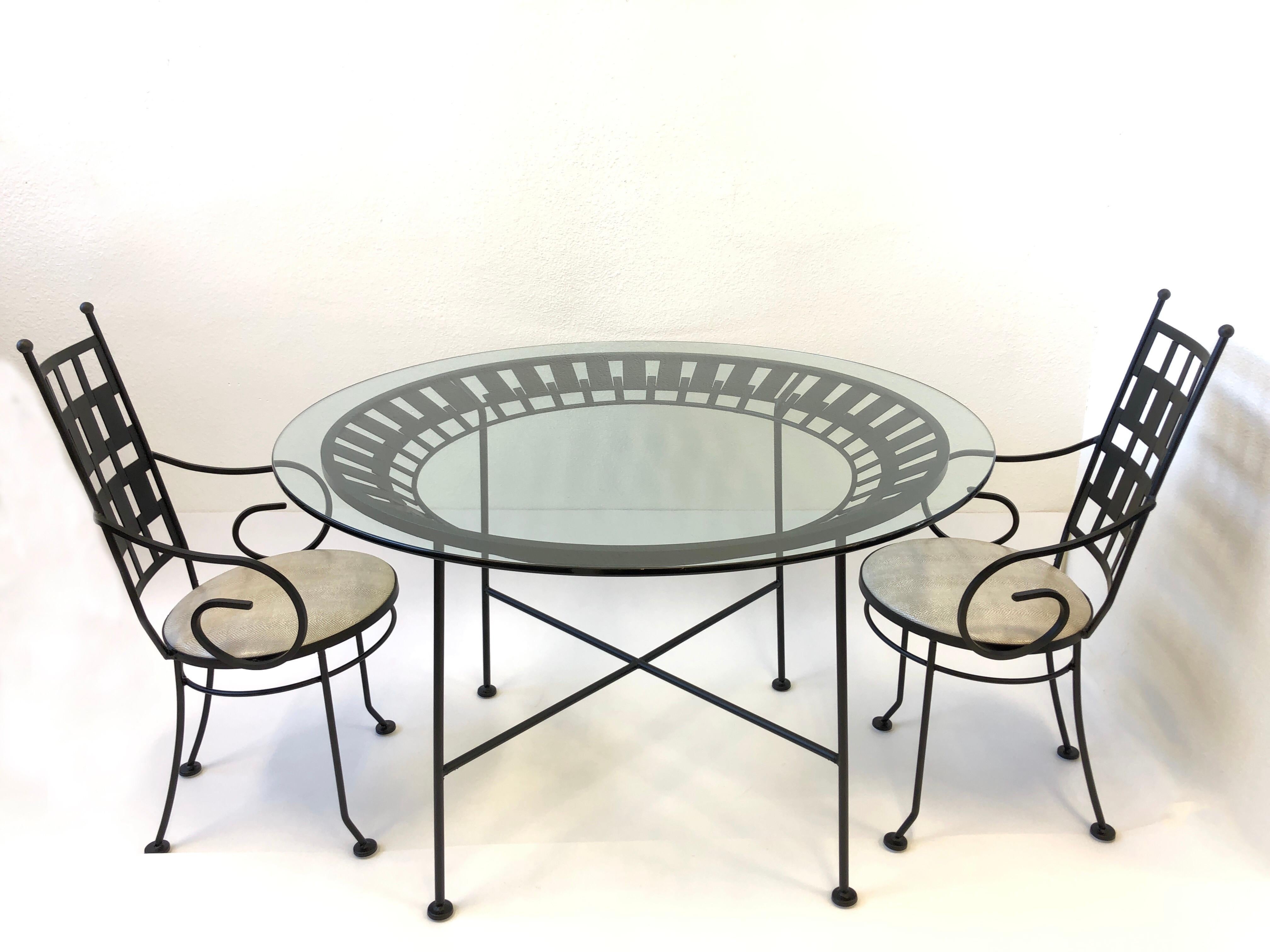 Glamorous high back armchair and table design by Arthur Unamoff in the 1960s. The set is constructed of steel that has been newly powder coated satin black, new 48” diameter 1/2” thick glass top and seats on chairs are newly recovered in a off-white