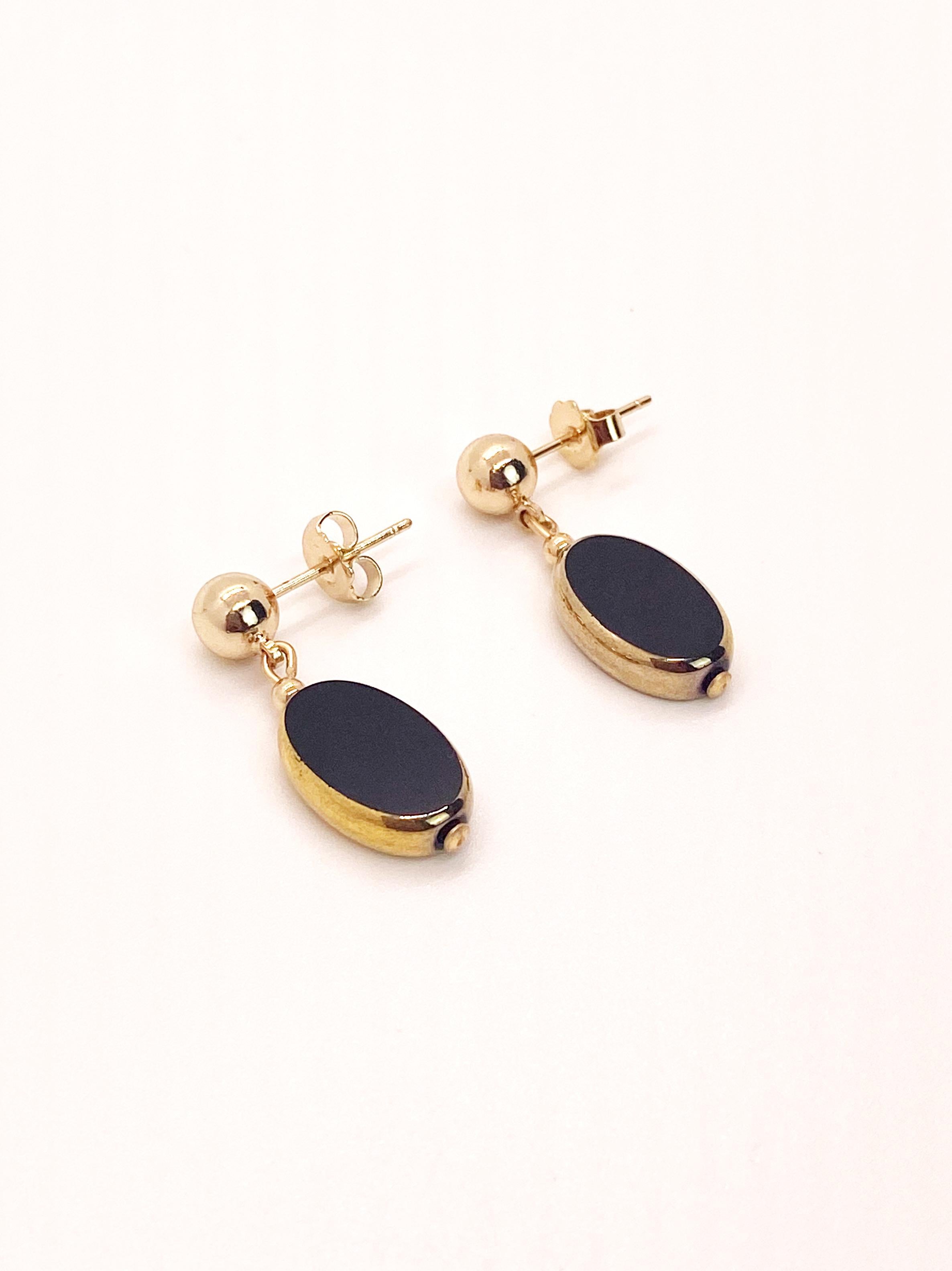 Cuentas ovaladas negras de cristal vintage alemán con bordes de oro de 24 quilates colgando de un pendiente con bola de 6 mm y baño de oro de 14 quilates. 

Las cuentas de vidrio vintage alemanas se consideran raras y coleccionables, de entre 1920 y