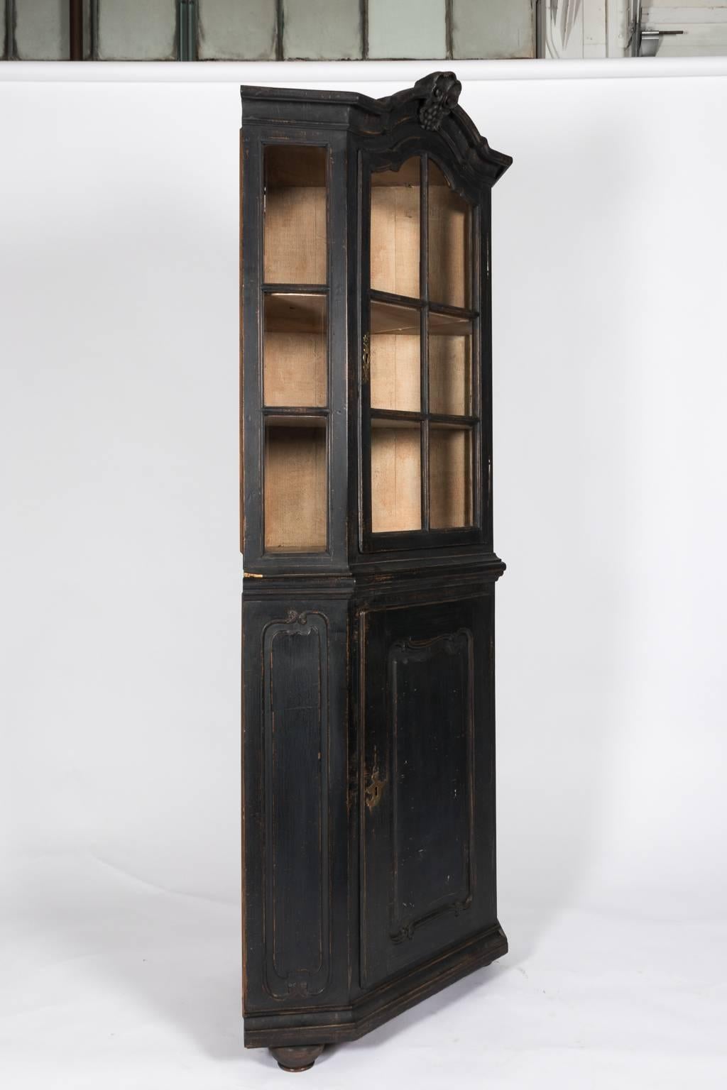 Black painted Rococo style corner cabinet with glass fronts and a curved top, circa late 18th century. The bottom features a profiled door.
 