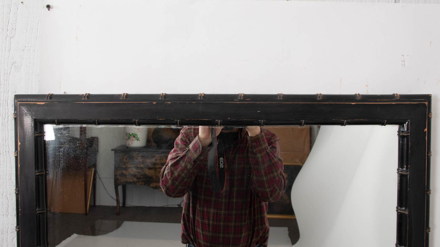 Hollywood Regency style faux bamboo mirror in a distressed black painted finish, circa 1960s. Please note of wear consistent with age. Made in the United States.