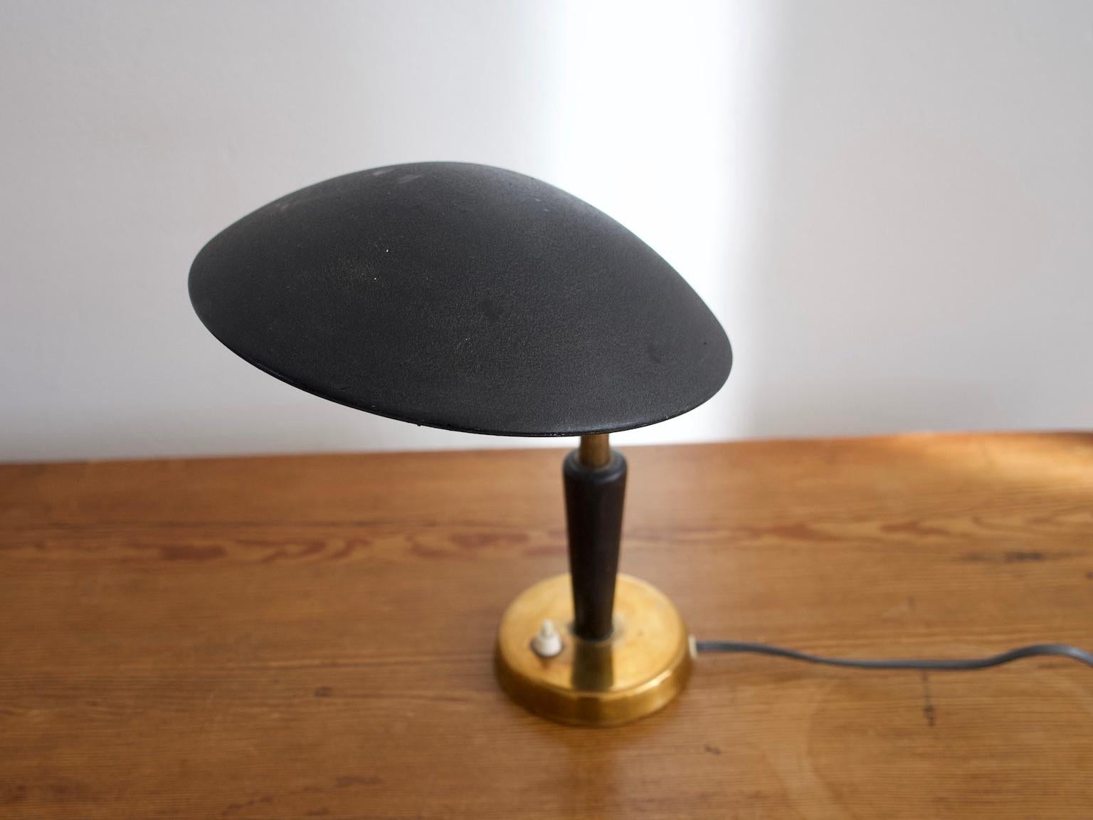 Small table lamp from the 1930s with adjustable black metal screen, brass base and rod and black painted wood detail. Manufactured and stamped by Nordiska Kompaniet. European plug.