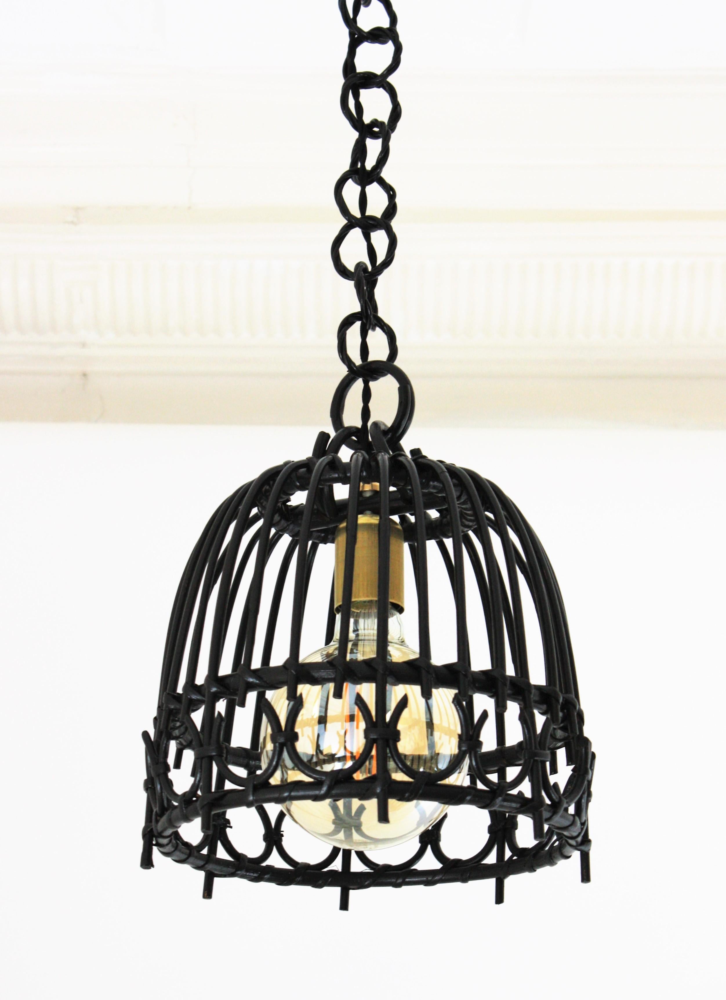 Midcentury Spanish rattan and bamboo bell shaped pendant hanging light finished in black patina, Spain, 1960s
This cool handcrafted rattan ceiling lamp / pendant hanging light has geometric decorative accents. It hangs from a round rings rattan