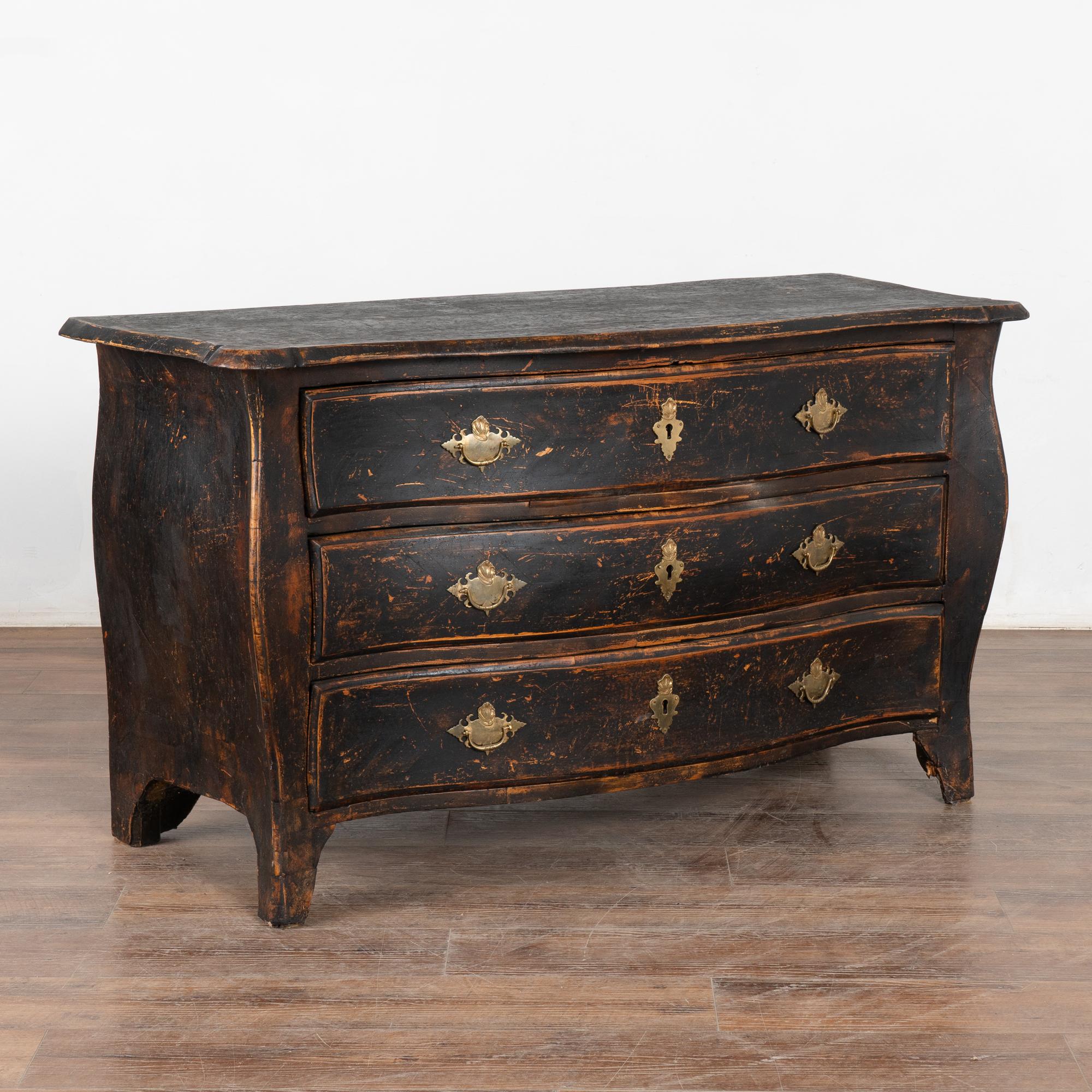 It is the bombay curves and feet turning gently outwards that draws one to this dramatic chest of drawers.
Restored, strong stable and ready for use. The old but later applied black paint has been distressed and reveals the age and character of this