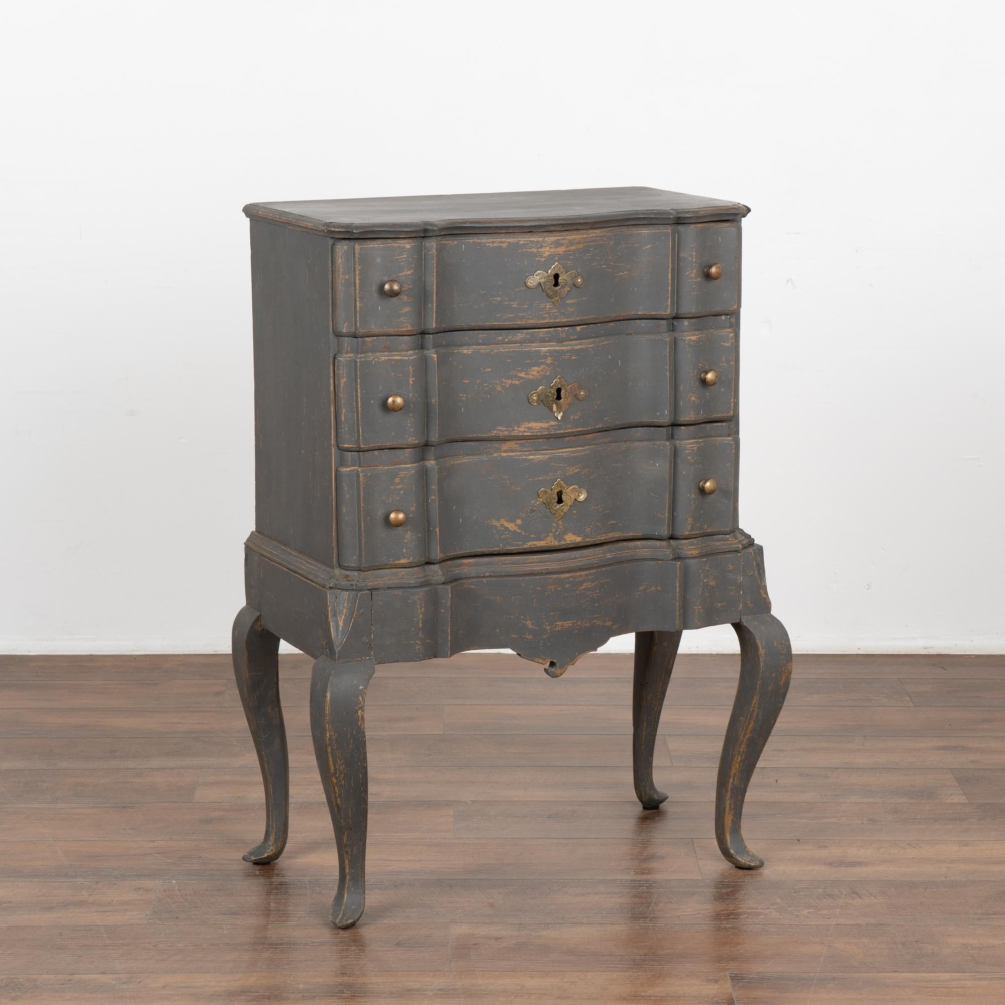 A small oak rococo chest of three drawers with brass key escutcheons. The scalloped edge is carried down through the 3 drawer fronts and bottom apron resulting in an elegant chest all resting on four elongated cabriole legs.
The newer,