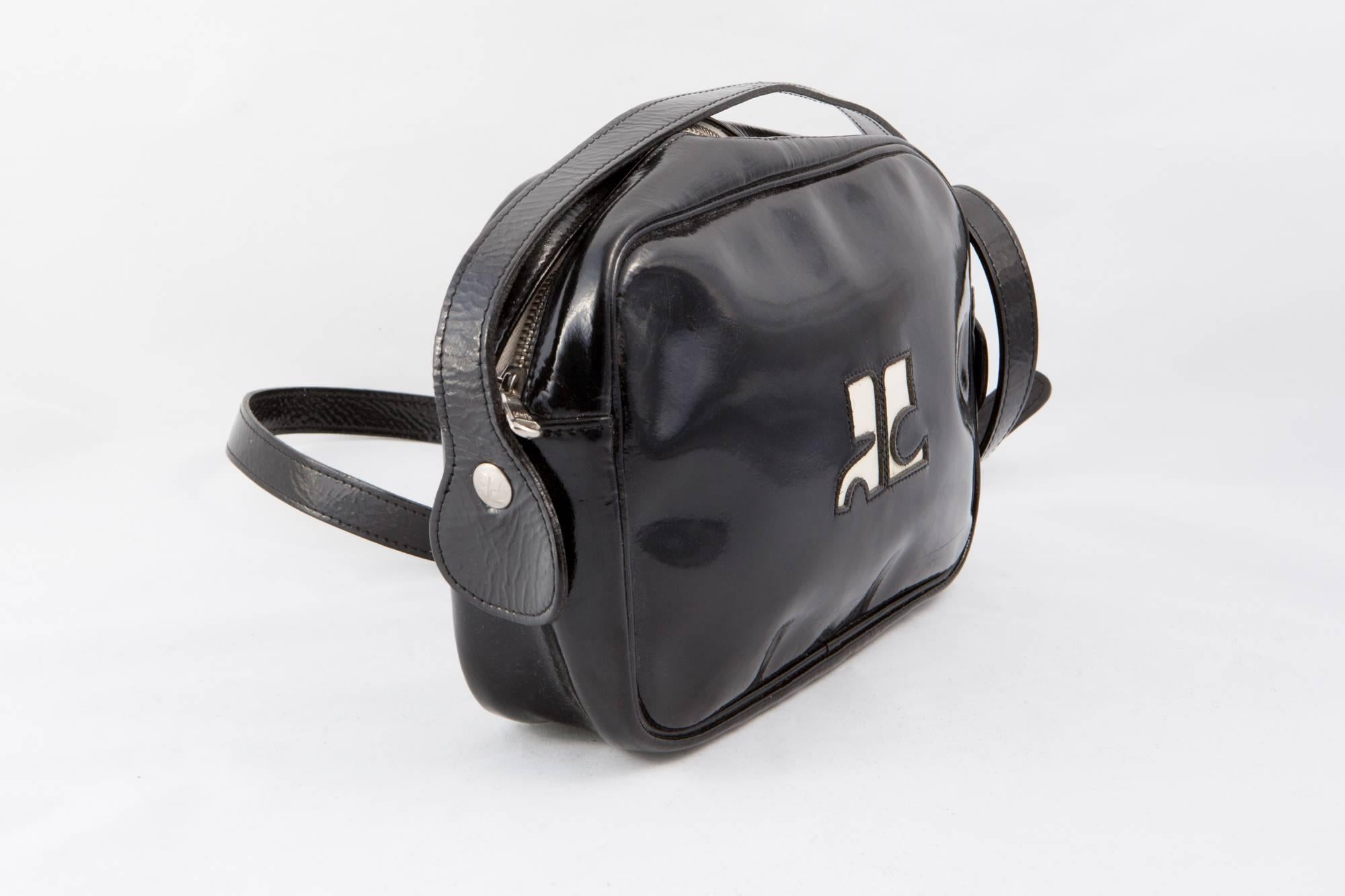 Iconic black patent Courrèges crossbody bag featuring a top zip opening, a camera shape, a top zip opening, a front white tone logo, a long adjustable shoulder strap (in. (122 cm), an inside white lining with an inside pocket.
In good vintage