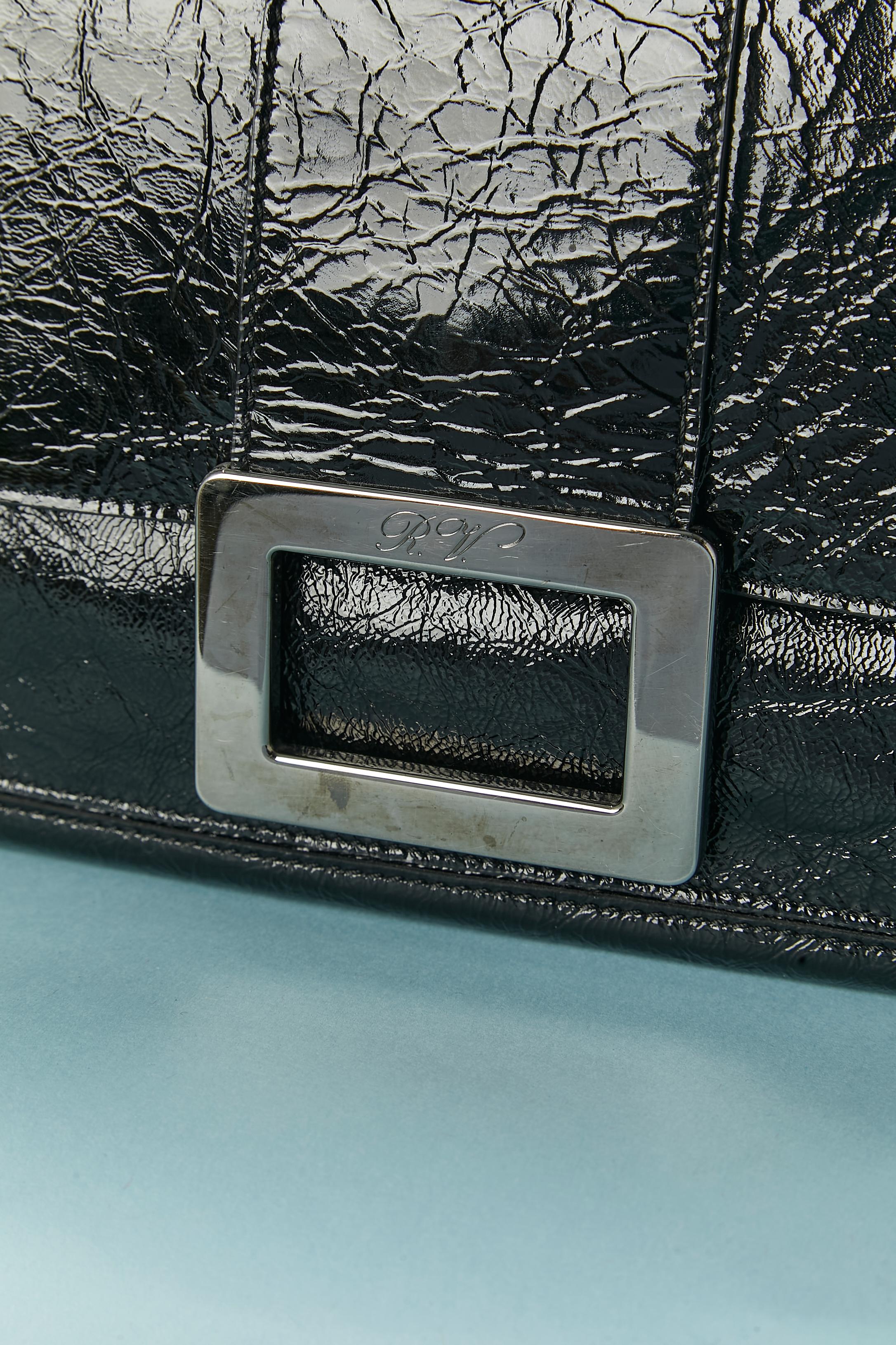 Black patent leather shoulder bag. Snap closure under the flap with silver hardware decorative buckle. One flat pocket under the flap and one flat pocket on the back of the bag. Branded nylon lining. One small pocket inside the bag with zip closure.