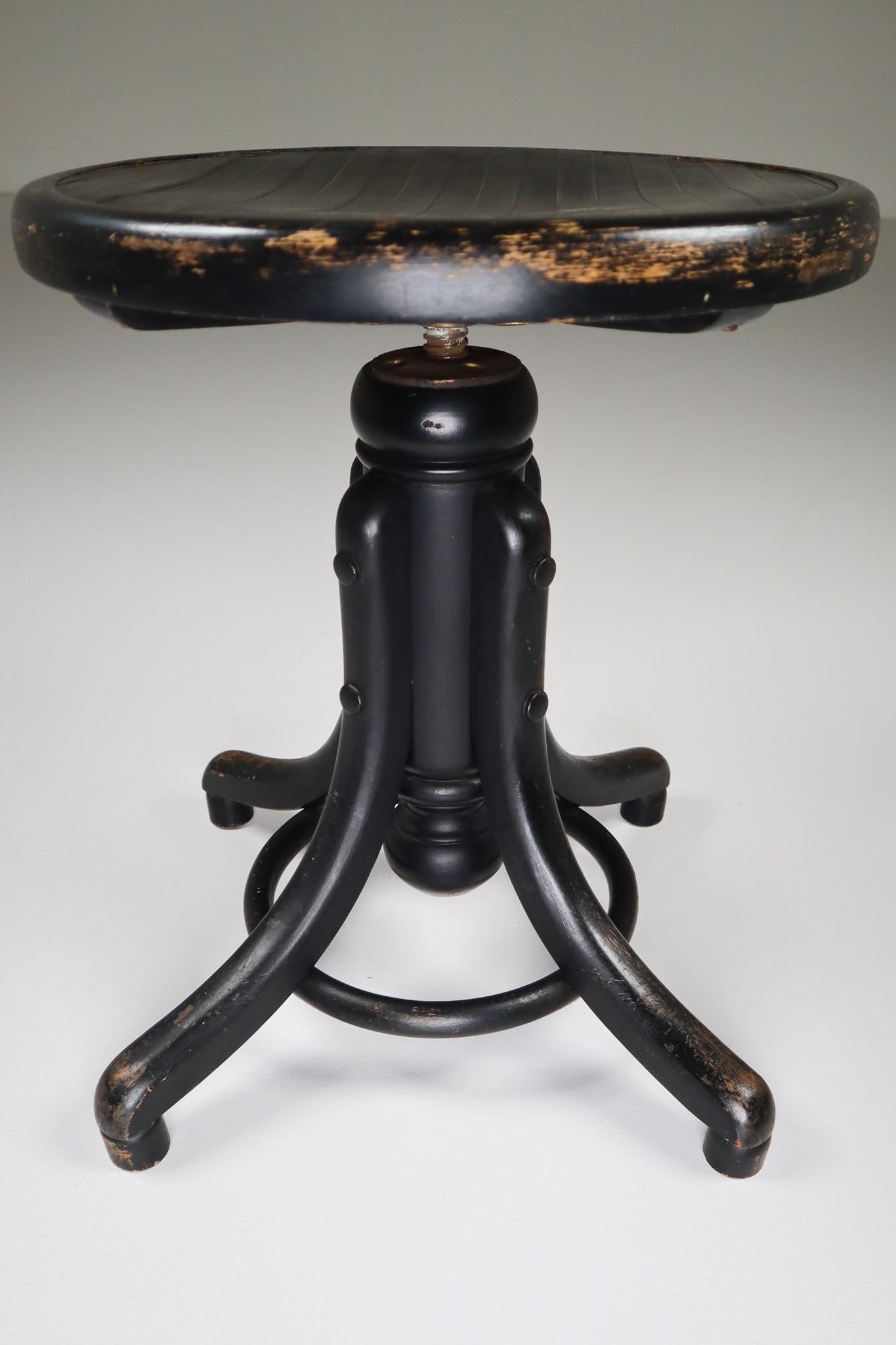 Black patinated adjustable piano stool by Thonet. Bentwood legs with turned wood vertical standard, and wood disk form seat. Seat spins to adjust height (Total H in upper position 66 inch x 44 cm lower position). Originally designed as piano stool,
