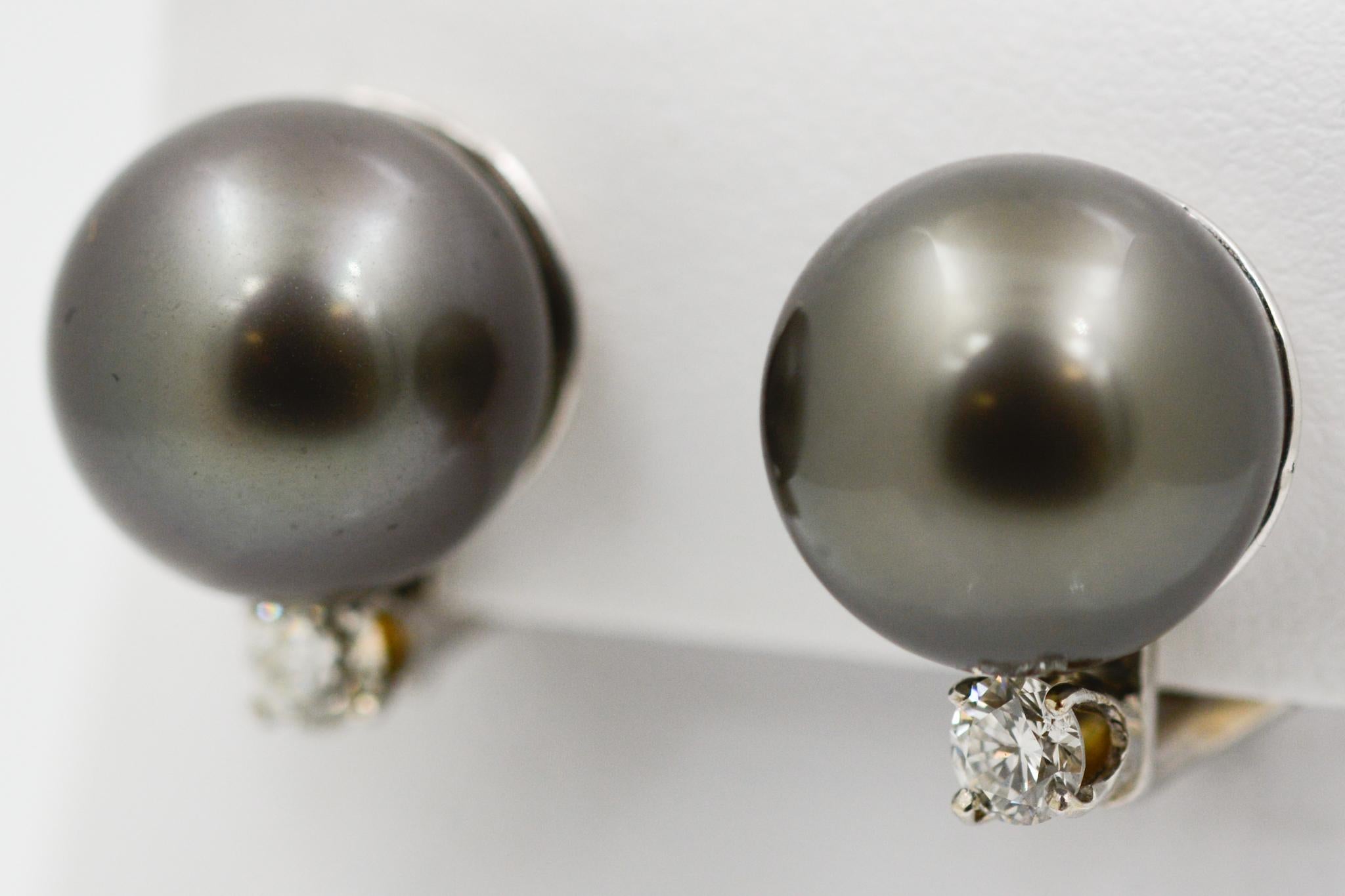 These 14 karat white gold earrings feature two black pearls measuring 13.29mm in diameter and are accented with two round brilliant cut diamonds weighing 0.50 carats with G-H coloring and VS clarity. 