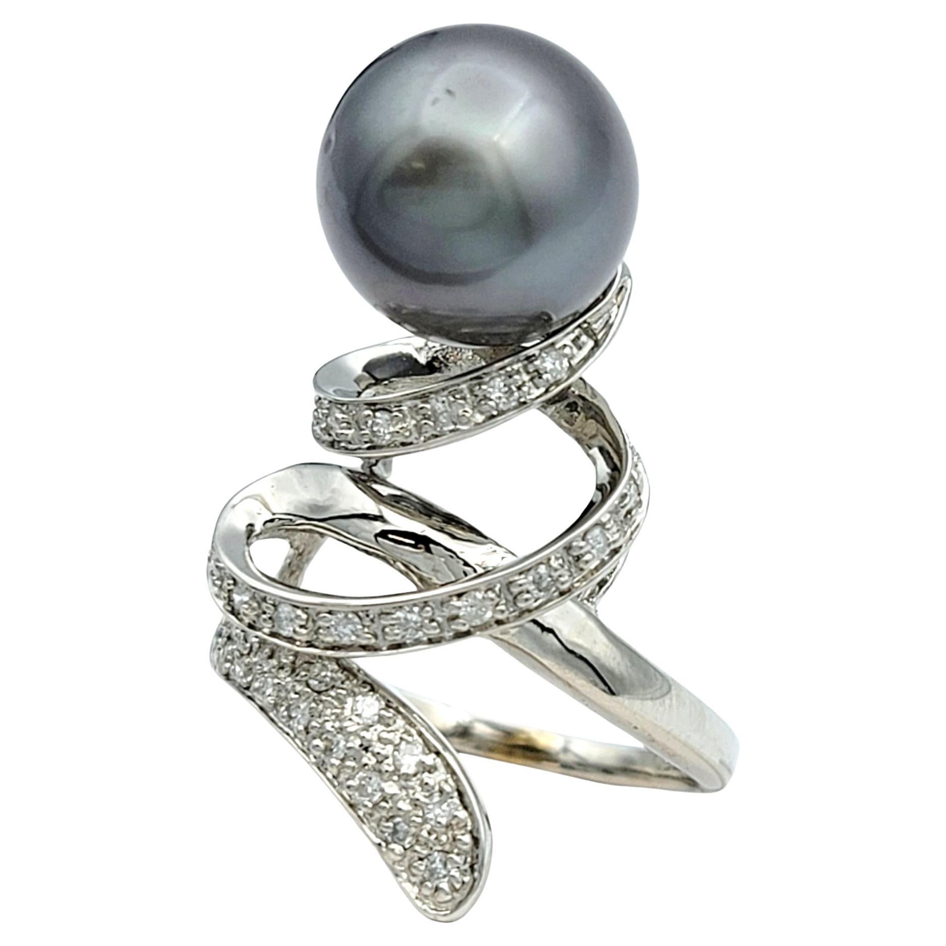 Misura dell'anello: 7

Questo accattivante anello cocktail con perle nere e diamanti vanta un affascinante design a spirale ed è incastonato in un lussuoso oro bianco da 18 carati. Il suo cuore è costituito da una perla nera lucente, che emana