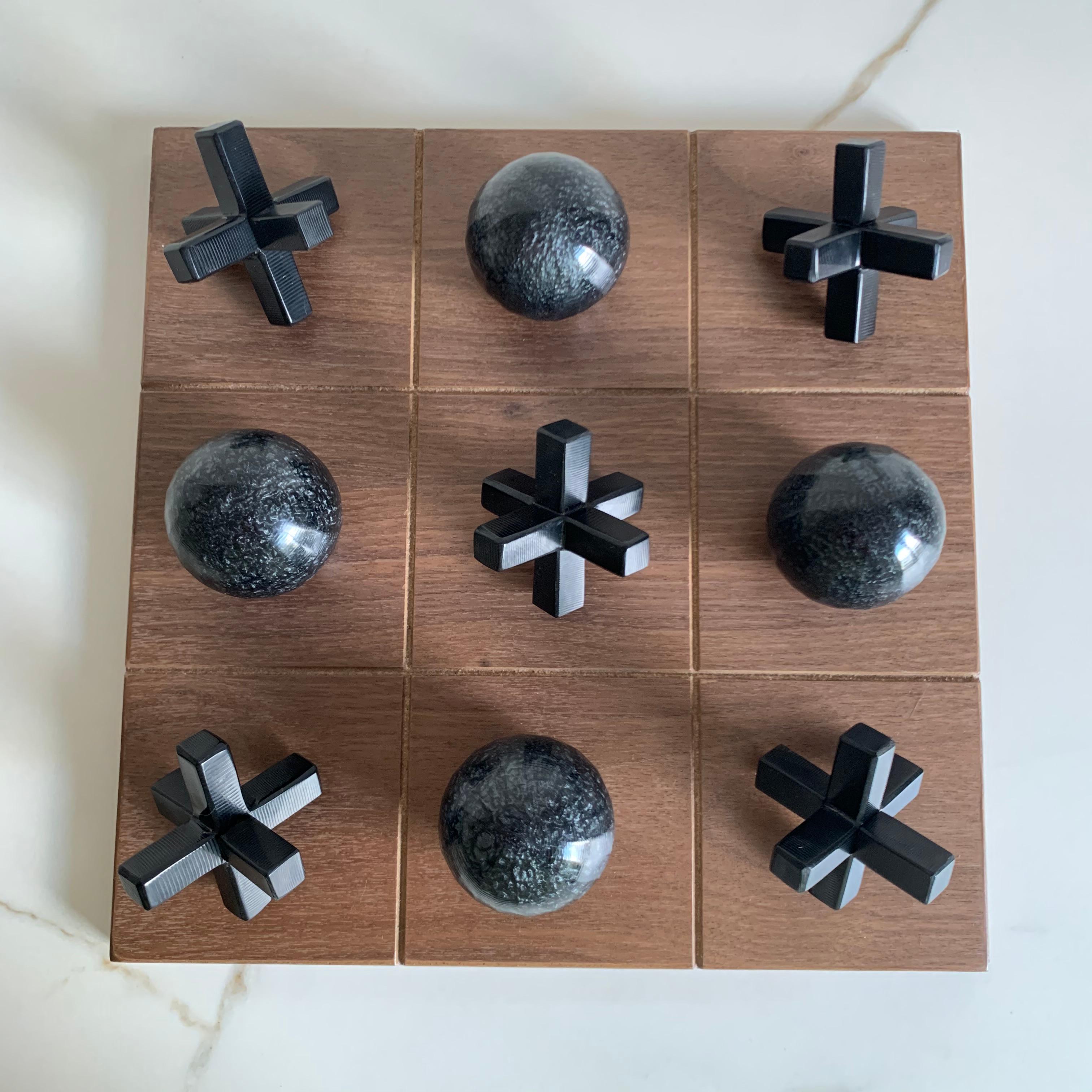 Unser Tic Tac Toe ist eine schöne, moderne und lustige Version des klassischen Spiels. Die dreidimensionalen Stücke sind aus schwarzem Perlmutt und schwarzem Harz handgefertigt und das Brett ist aus Eichenholzfurnier gefertigt. Es wird das coolste