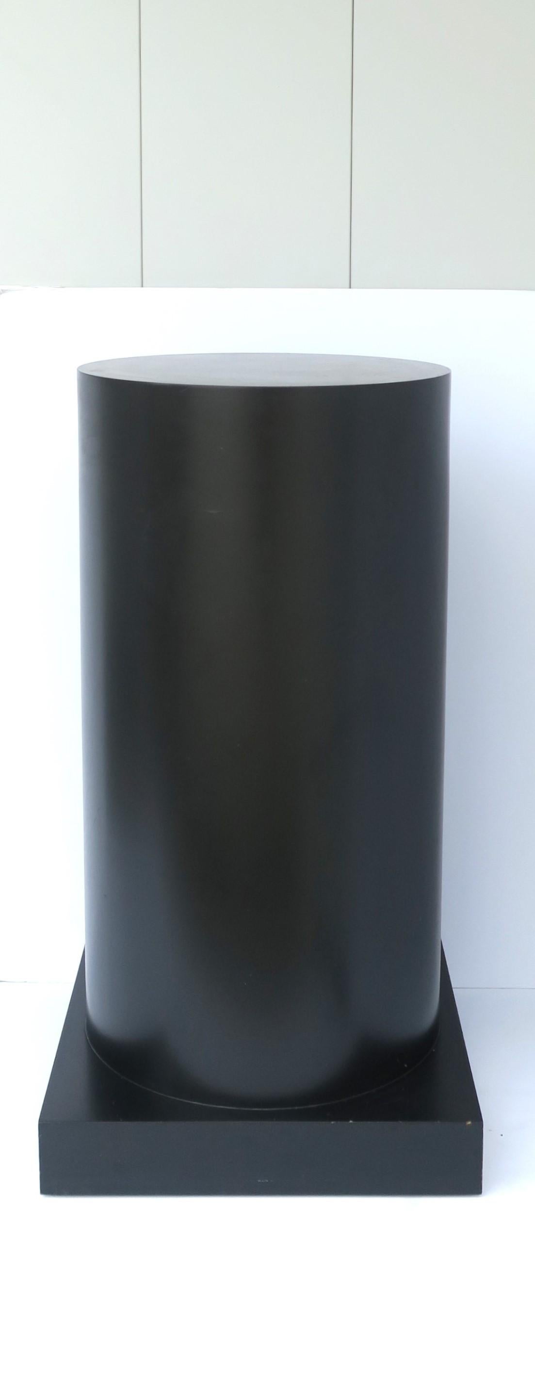 A relatively large black cylindrical pedestal column stand with square base, in the modern style or Post-Modern period, circa late-20th century, 1980s. A great piece to hold/display sculpture, plant, etc. Piece is a nice size. Dimensions: Square