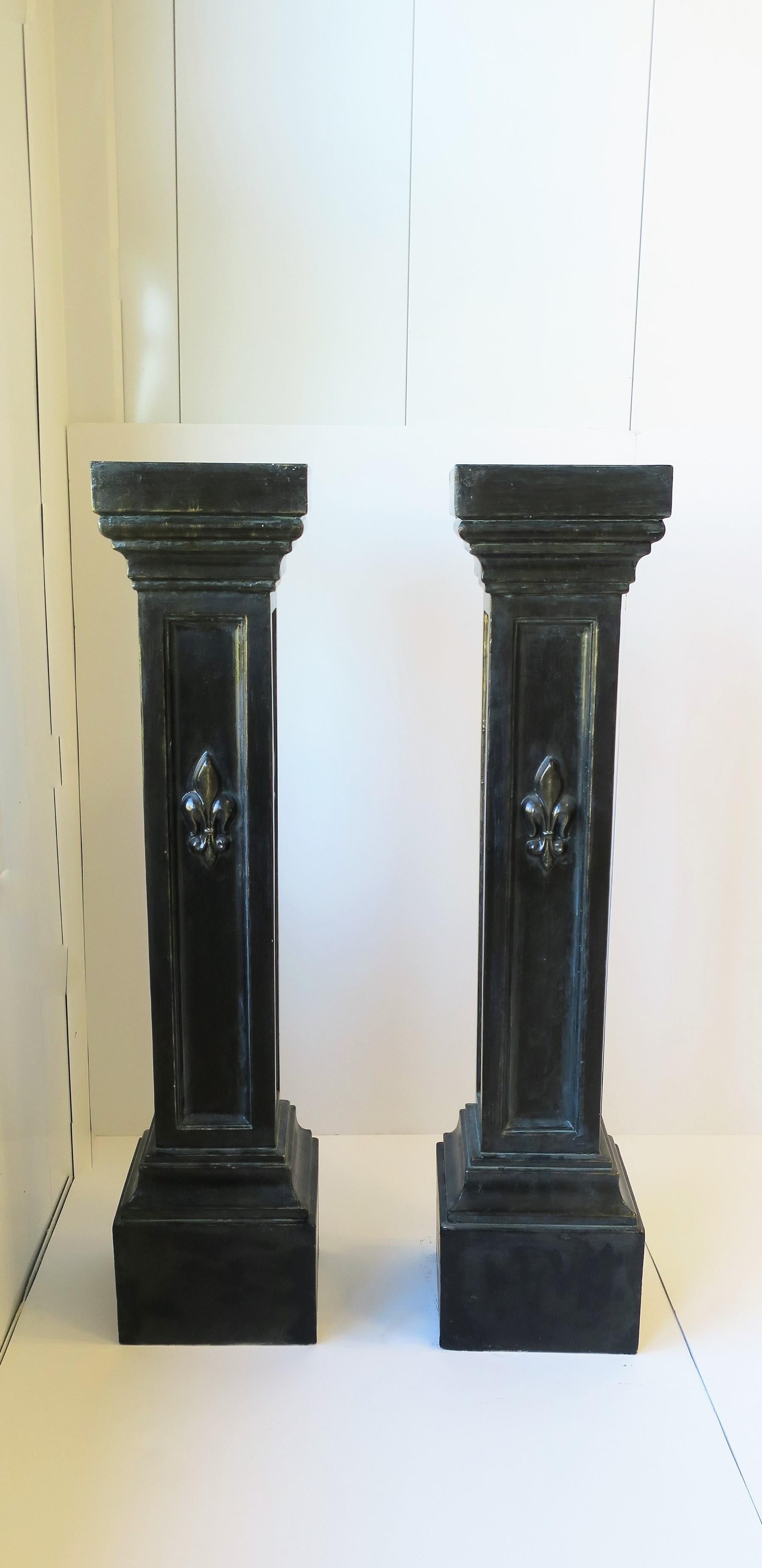 A beautiful pair of black painted plaster column pillar pedestal stands with French fleur-de-lis design, circa 20th century. Beautiful as standalone pieces or with sculpture, plant, art, design, etc. 

Dimensions: 
37.63