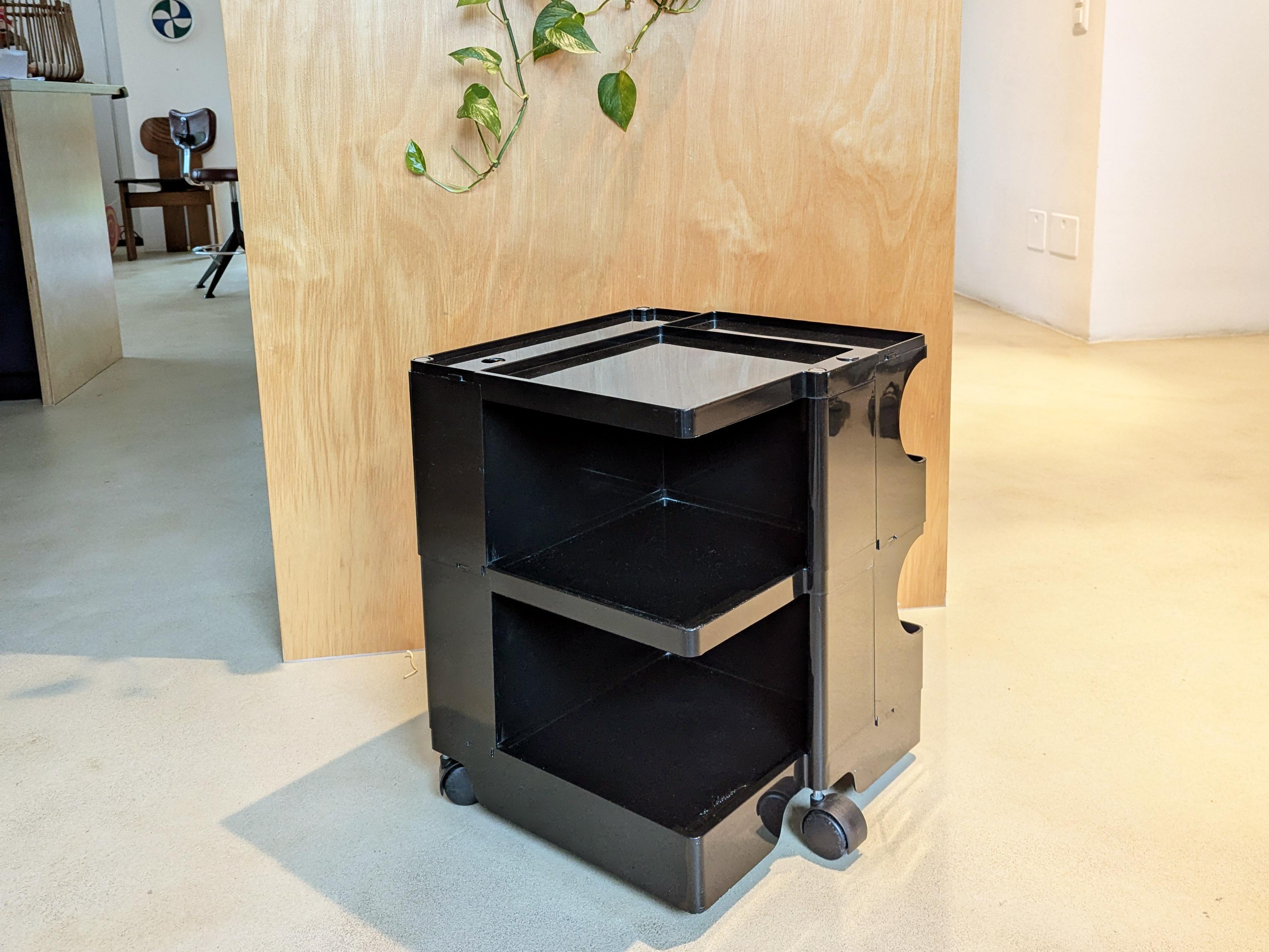Low version of the Boby container designed by Joe Colombo in the 1960s. This is a black plastic container unit with 3 wheels and versatile storage compartments. Ideal for use as a bedside table, in a child's room, in a study or in a bathroom. There