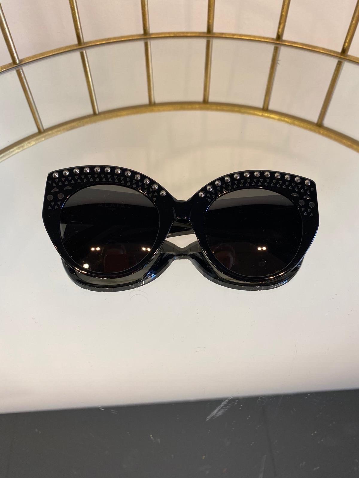 Black plastic sunglasses with studs. 
Width 14.5 cm
Height 6 cm
Wand 14.5 cm
Material: plastic
Black colour
With case but not original.