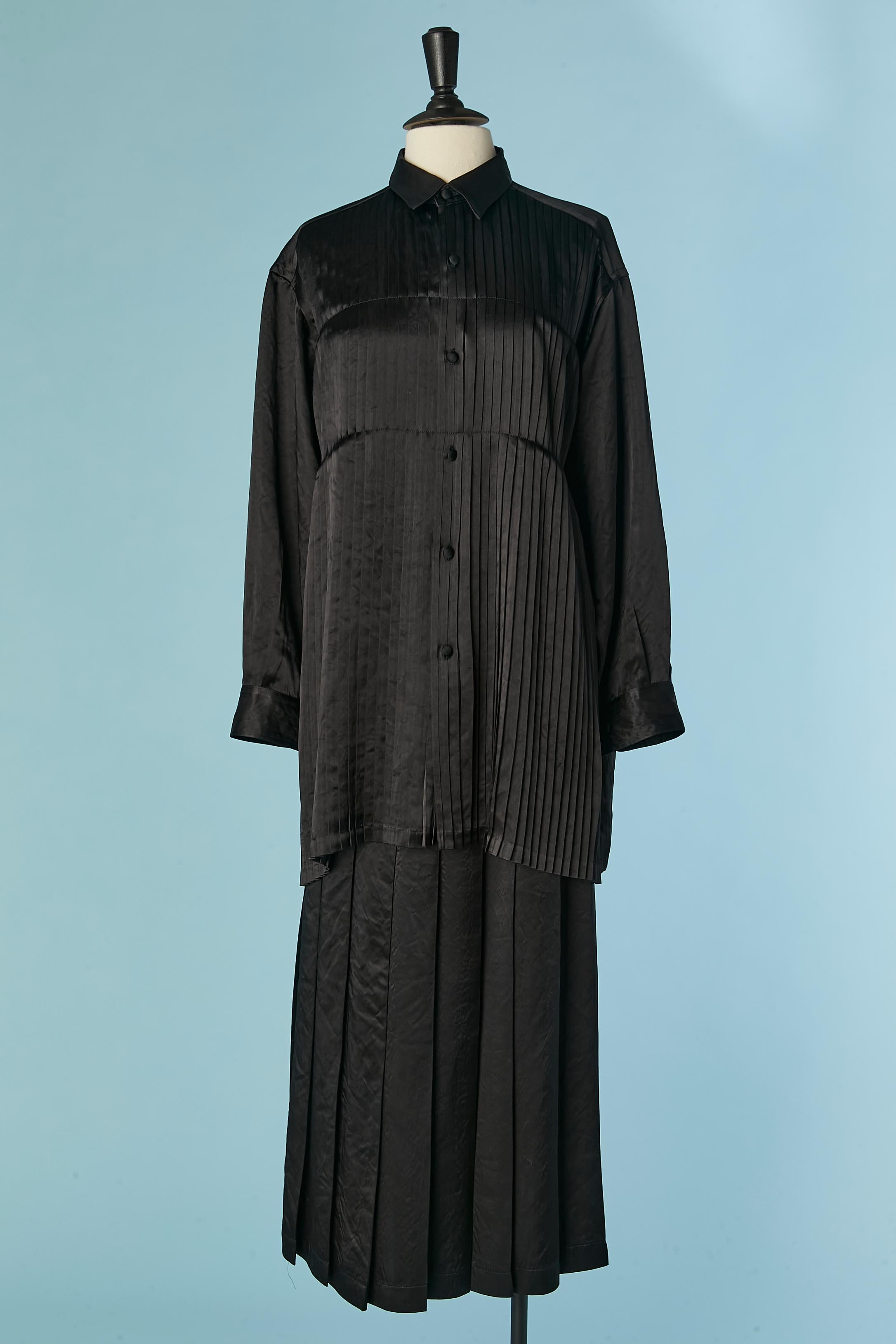 Un ensemble di camicia e gonna nera a pieghe. Composizione del tessuto: 100% Triacetato. 
Effetto 