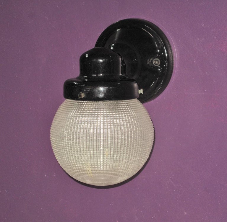 From the late 1920s or early 1930s is this versatile wall sconce light. Appropriate for a modern kitchen or bathroom or as a porch light for a cabin in the woods or bungalow in the city. Both the porcelain back plate and the Holophane globe are in
