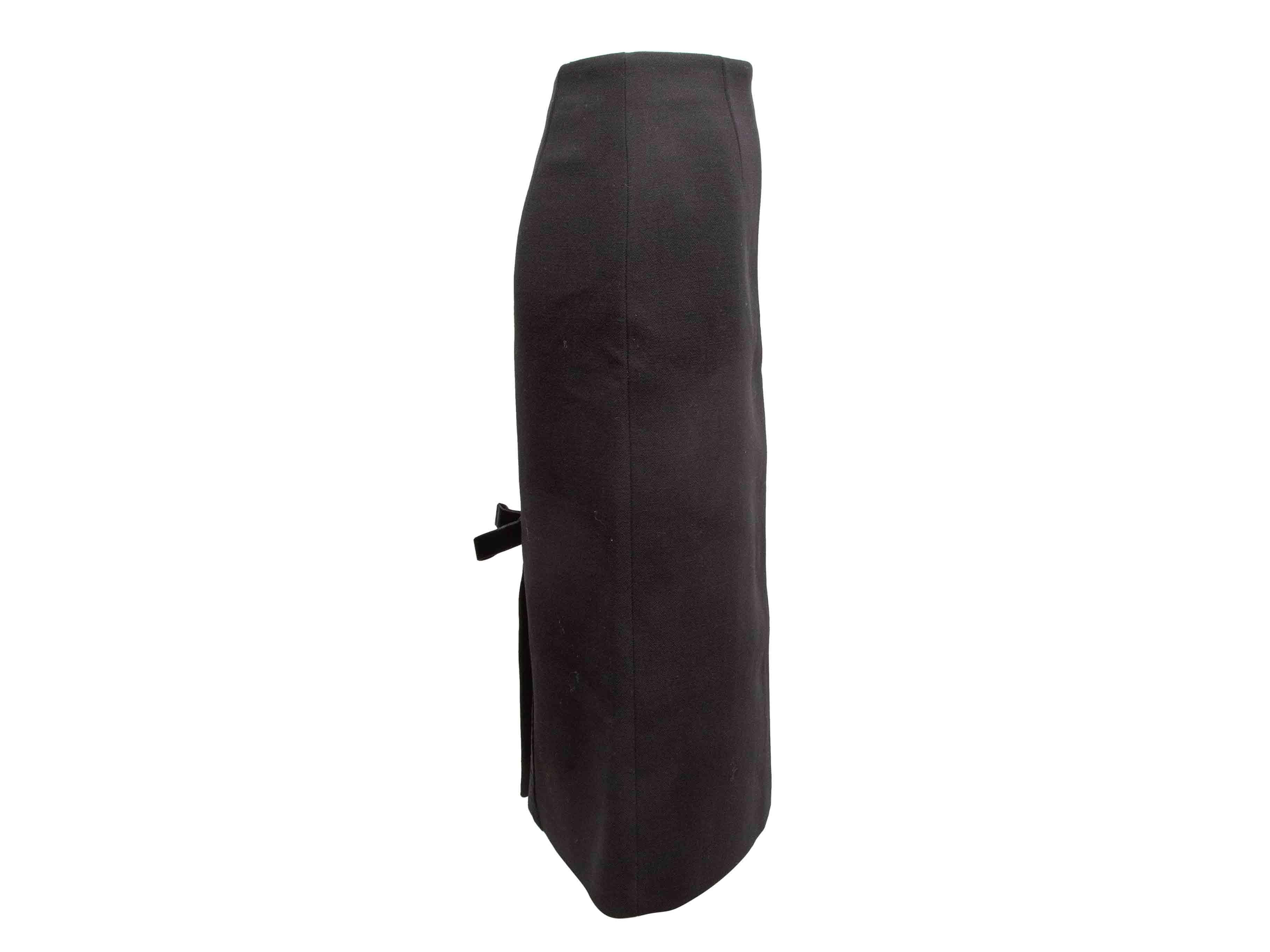Black virgin wool knee-length pencil skirt by Prada. Bow accent at back hem vent. Side zip closure. 26