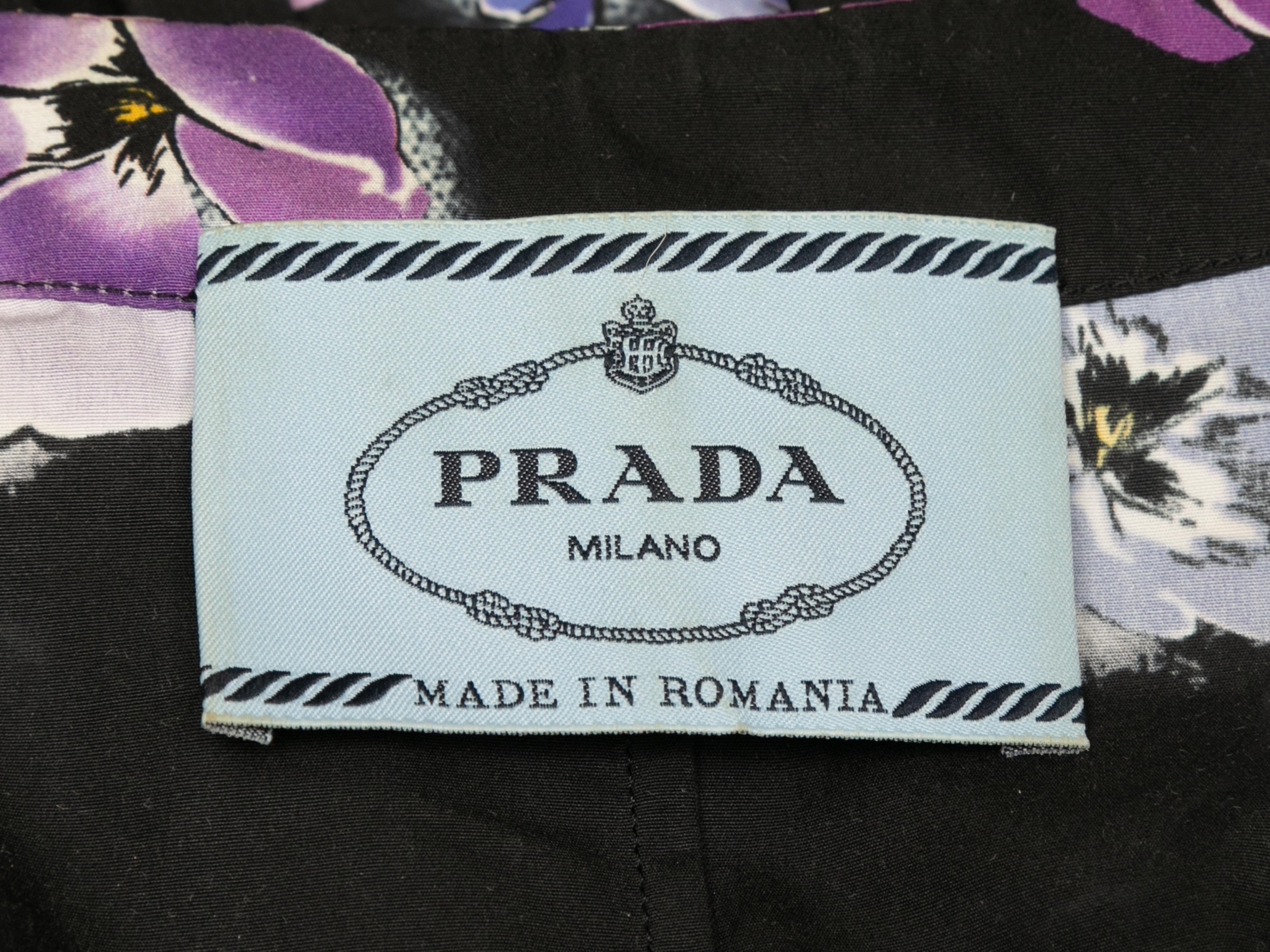 Black and purple pansy printed sleeveless dress by Prada. Crew neck. Sash tie at waist. Button closures at center front. 40