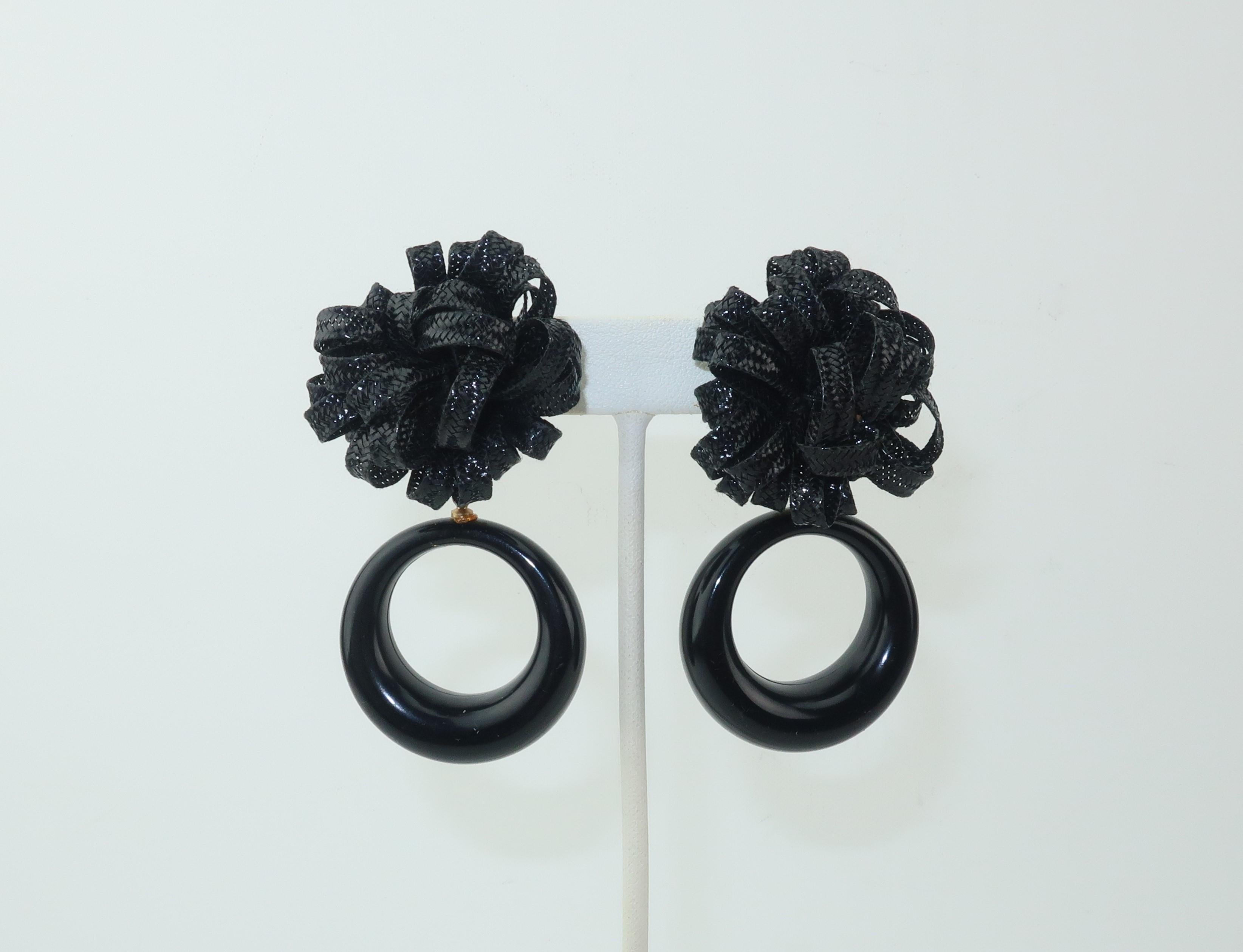 Cha cha charming!  These clip on earrings are a whole lotta fun with a synthetic raffia base providing a pouf for the black plastic dangle hoops.  They are perfect for adding a little whimsy to cocktail attire and equally ideal for adding pizzazz to