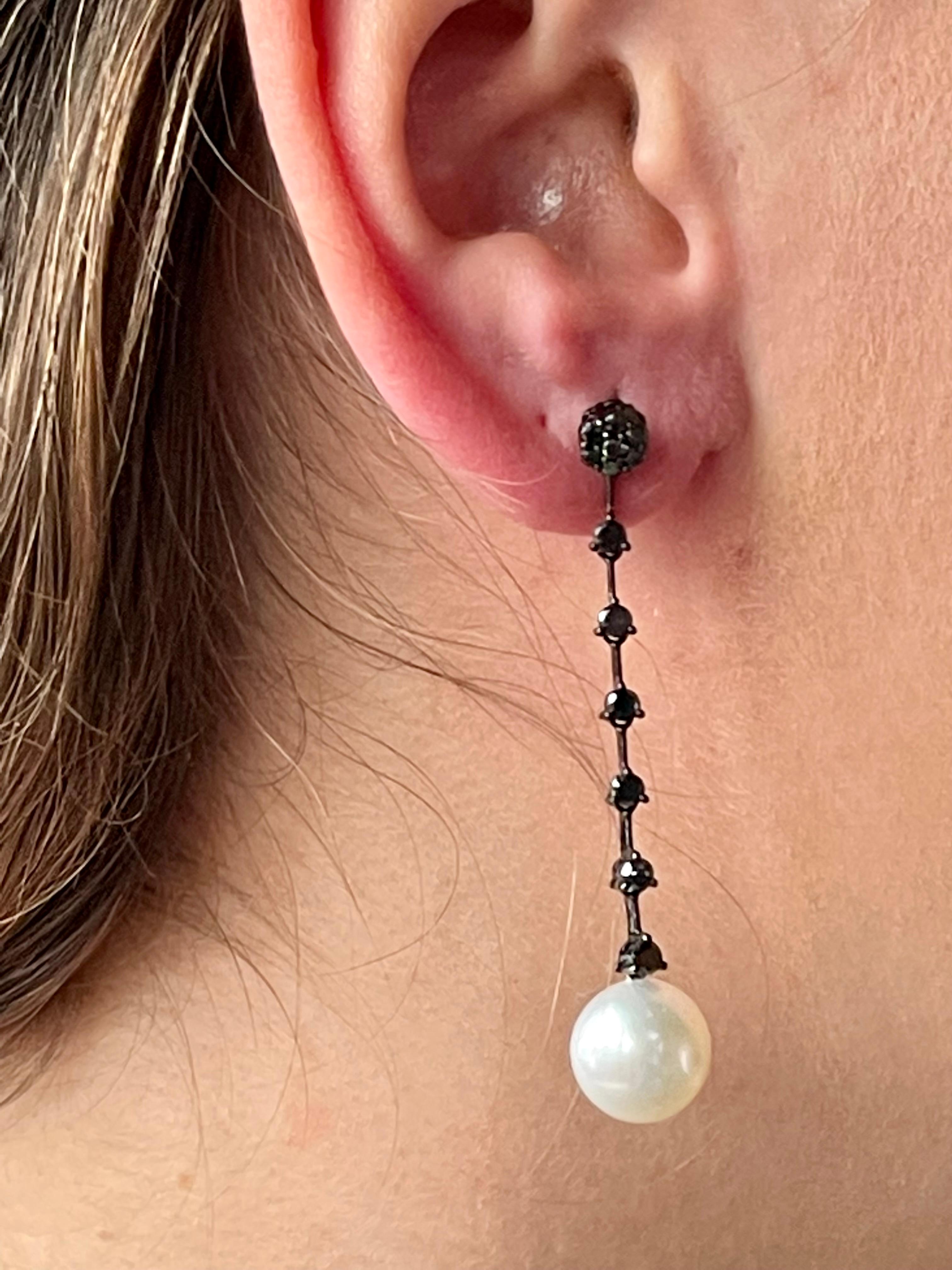 A pair of unusual straight single line dangle earrings set with 26 black brilliant cut Diamonds weighing 1.34 ct and 2 white South Sea Pearls (10.8mm in Diamenter) and nice lustre. 
Dramatic look with this color combination. 
The earrings measure