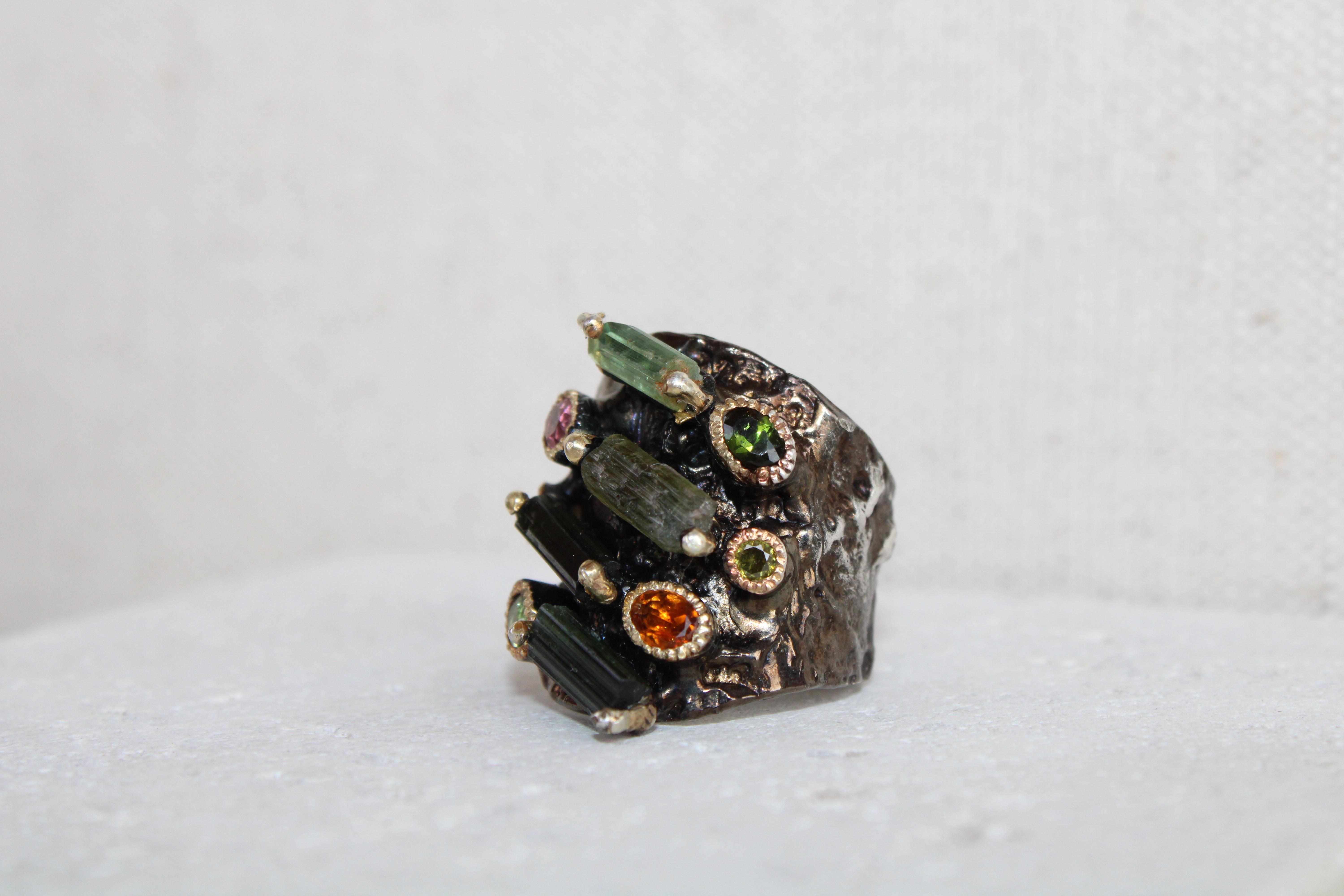 Unique and one-of-a-kind rough cut tourmaline cocktail ring. The ring is sterling silver with rhodium and gold plated. The ring also has oval cut tourmaline stones in orange, dark green, light green and pink in addition to the 4 rough cut