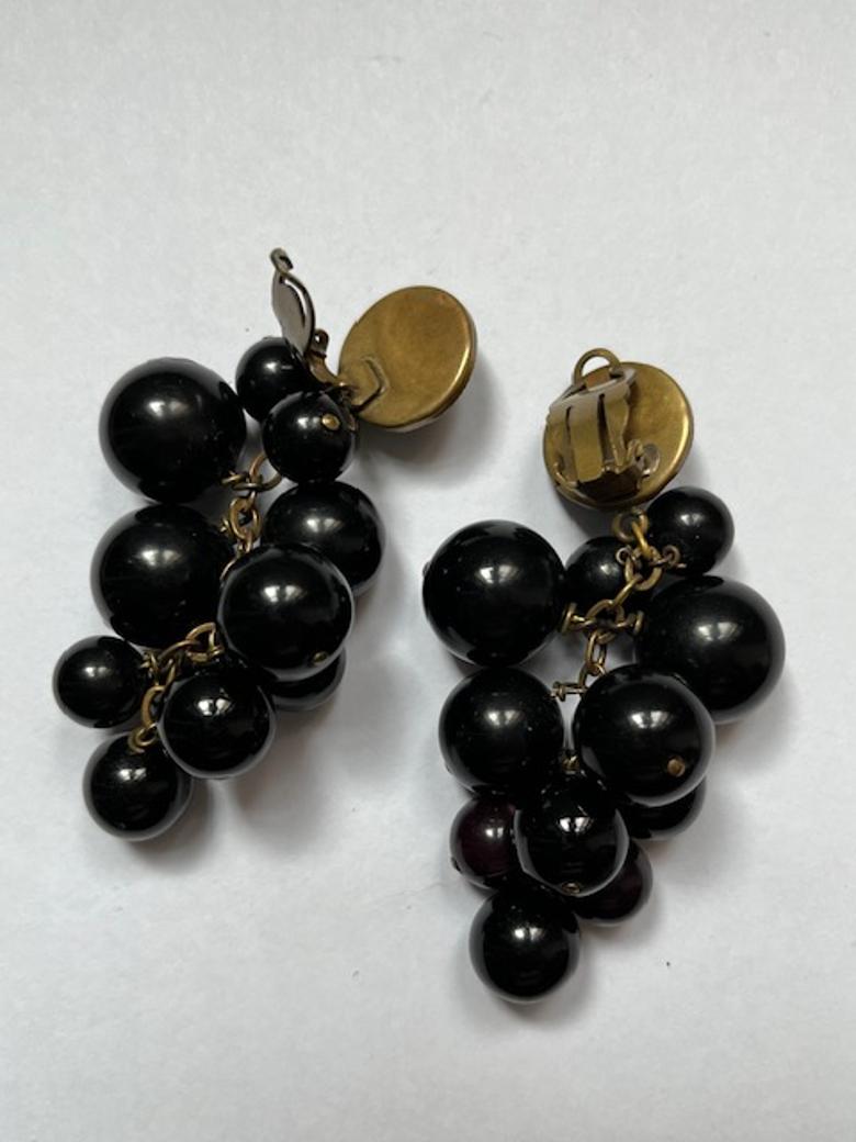 Cette étonnante paire de boucles d'oreilles à clip en forme de grappe présente un design audacieux et sophistiqué. Composée de sphères lisses en bakélite noire de différentes tailles, la disposition en cascade crée de la profondeur et un mouvement