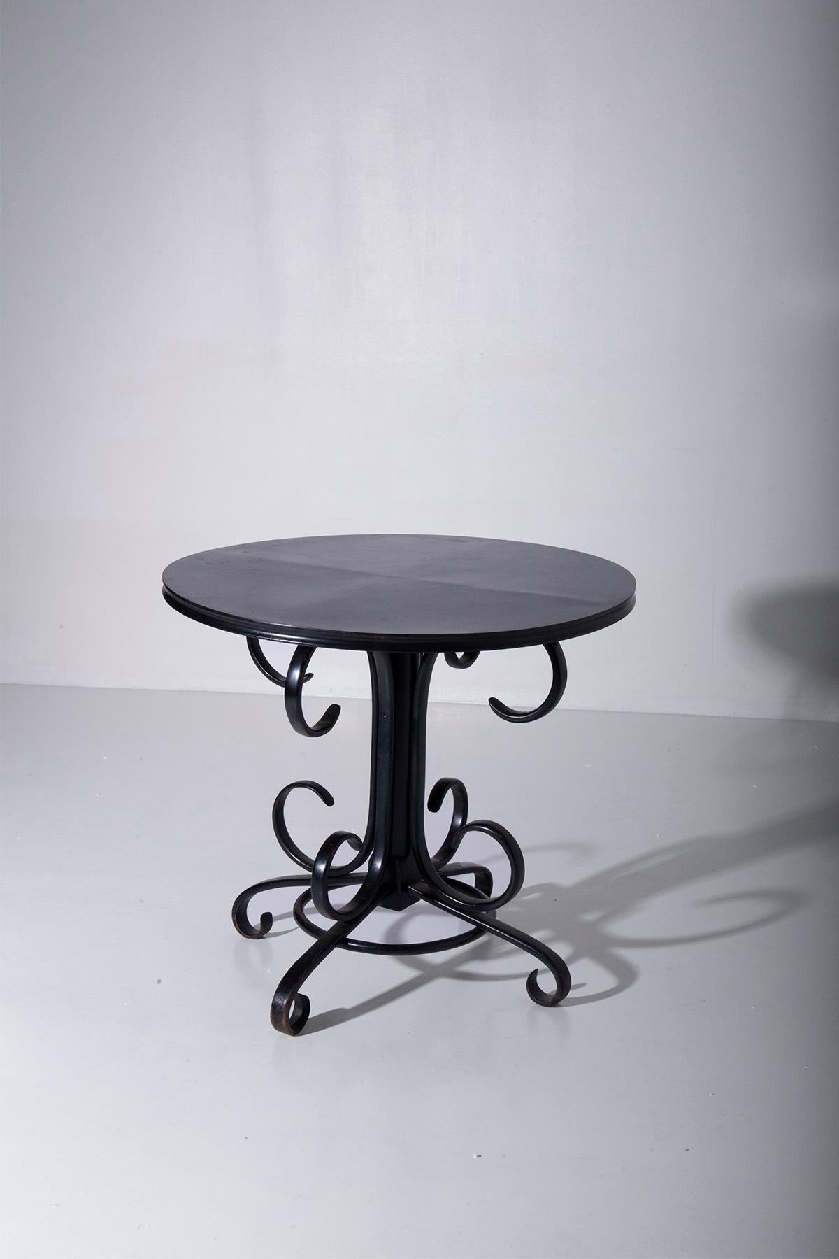 Imaginez une table centrale haute et élégante du début des années 1900, véritable témoignage de l'opulence et de la sophistication de l'époque Art déco. Cette pièce exquise est une œuvre de glamour en soi, fabriquée en bois laqué noir lustré.

Ce