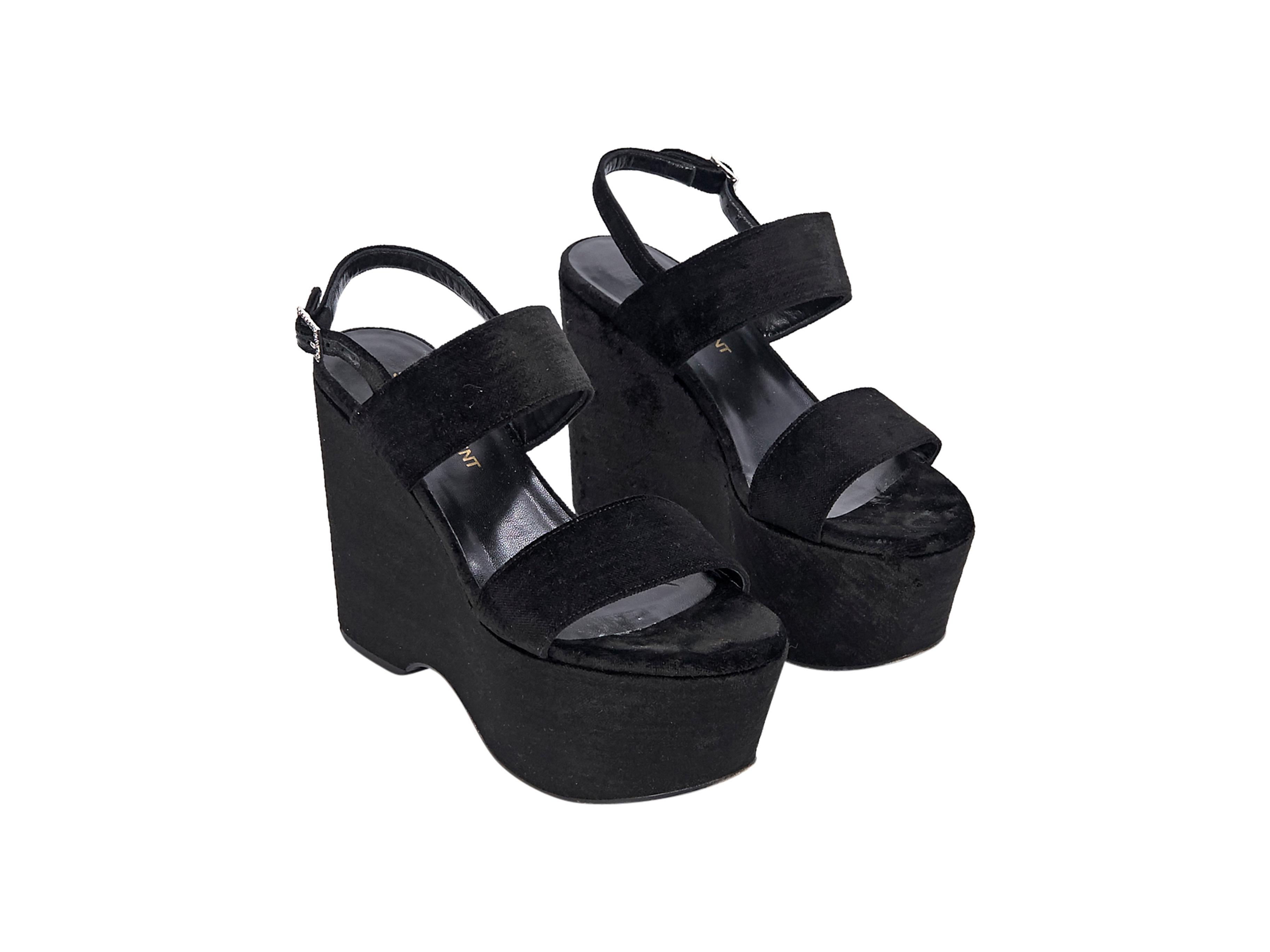 Product details:  Black velvet wedge sandals by Saint Laurent.  Adjustable slingback strap.  Open toe.  Towering wedge design.  5
