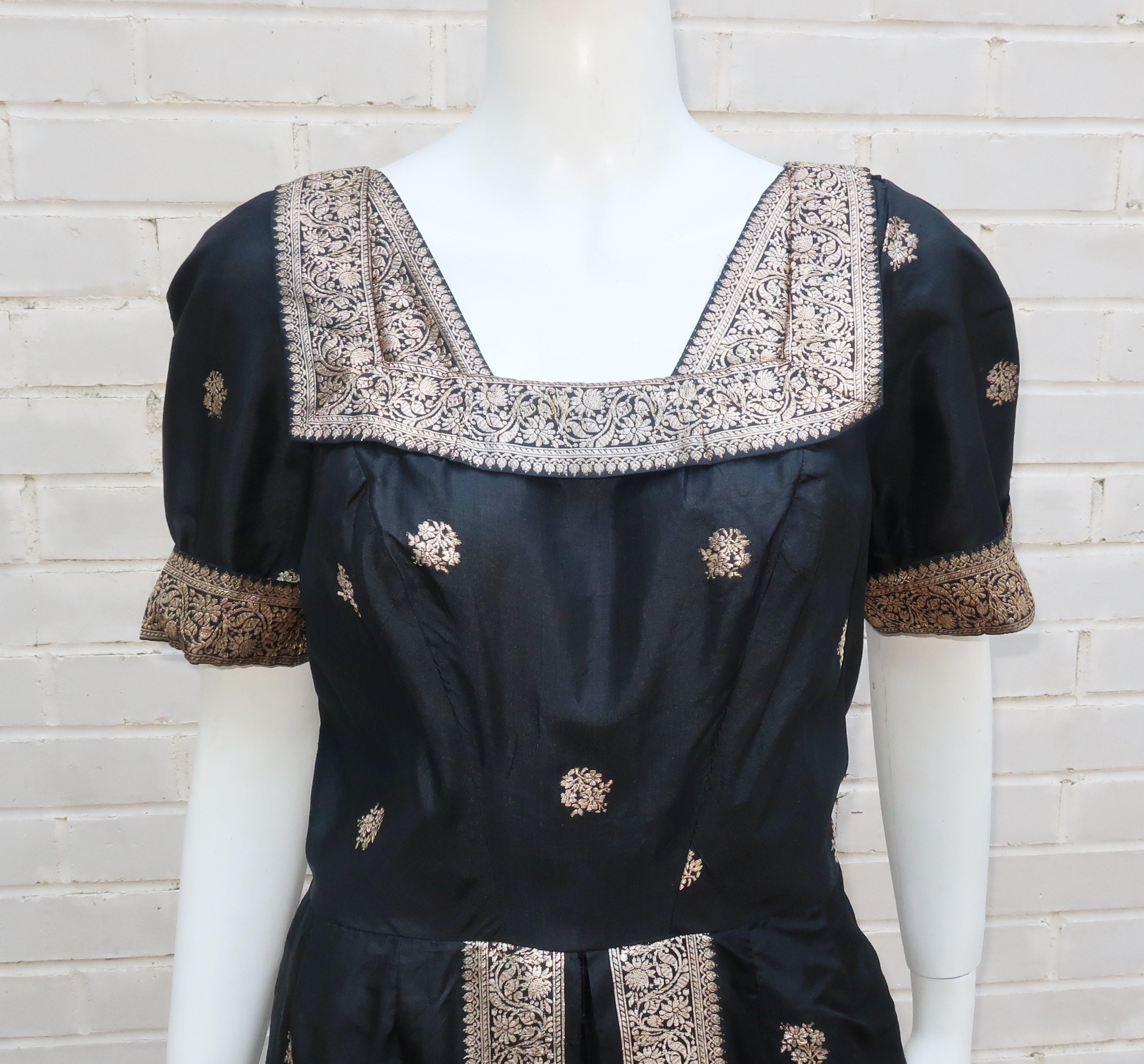 1950's cocktail dress in a black silk sari fabric with platinum paisley metallic accents.  The dress zips under one arm and features inverted pleating hidden under front flaps and a neckline embellished with a square collar at front and back.  No