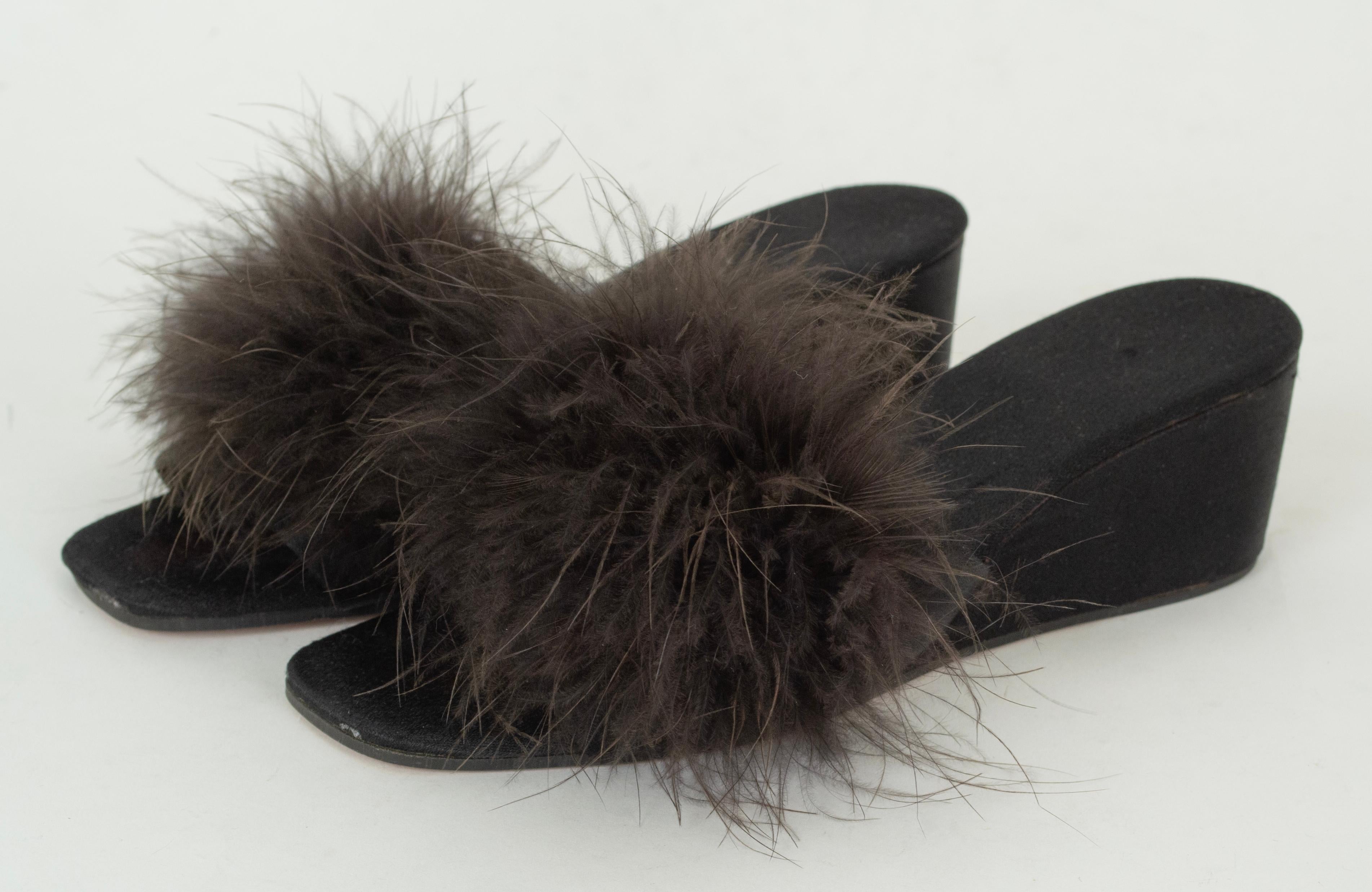 Aucun boudoir de vamp ne devrait être dépourvu d'une pantoufle mule en marabout. Il est vraiment dommage qu'ils n'aient jamais reçu l'attention qu'ils méritaient, car ils n'ont jamais été portés ni testés.

Pantoufle en satin noir avec empeigne en