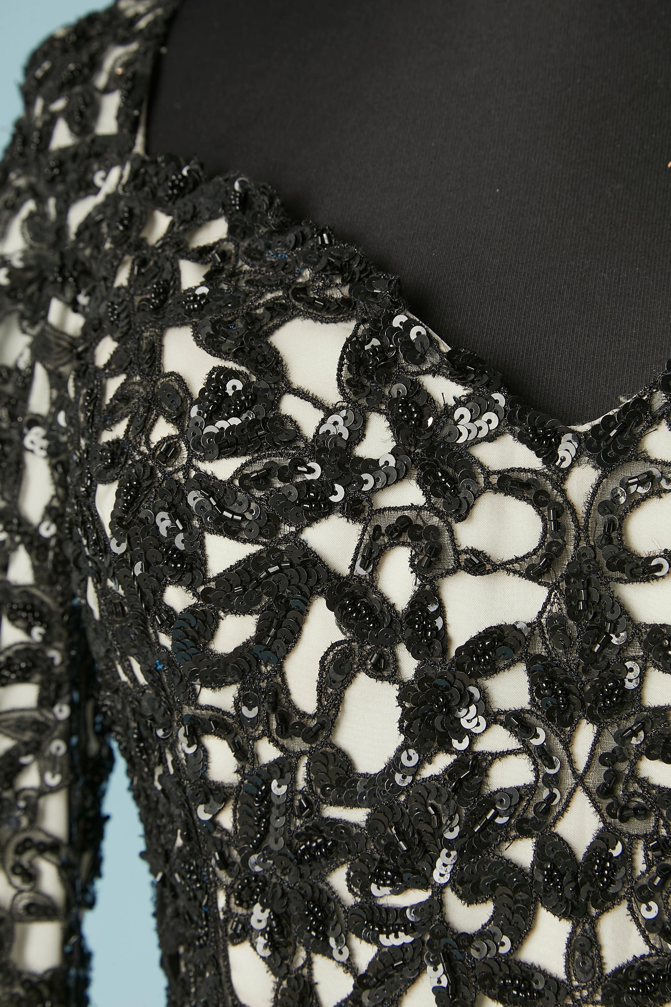 Applicazione di pizzo nero con paillettes su un abito da cocktail in seta color avorio. Bustier in tulle disossato all'interno dell'abito con reggiseno pad. Fodera in seta. Zip e gancio al centro della schiena. 
TAGLIA 2(Noi)  / XS 