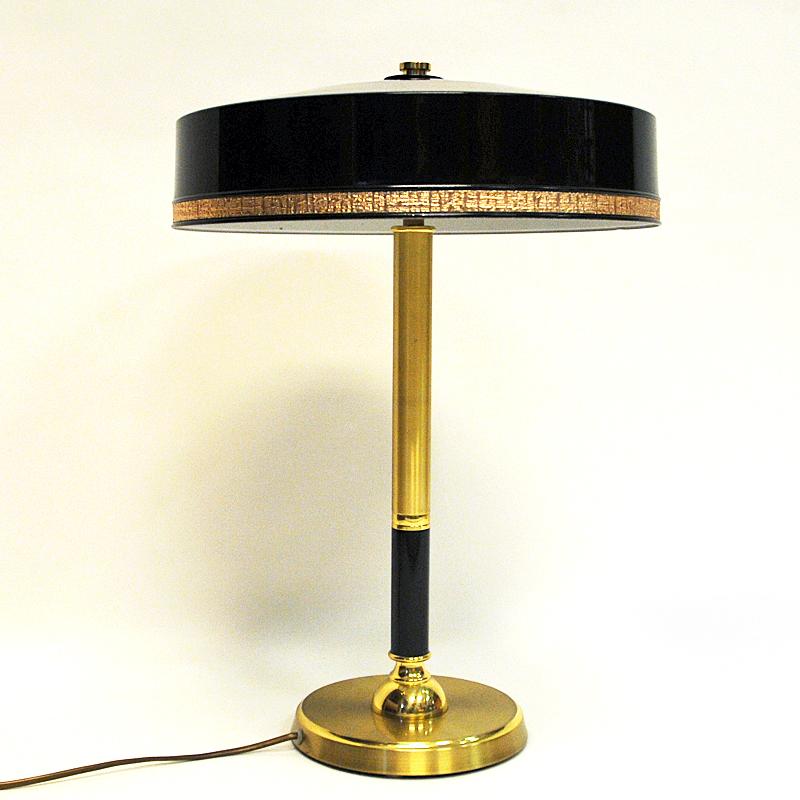 Black and brass tablelamp designed by C.E. Fors model B162 for EWÅ Värnamo, Sweden 1960s. Lovely design with a golden decor edge all around the lamps shade. Glossy black laquered stom and shade with two light points for optimal light. 
White inner