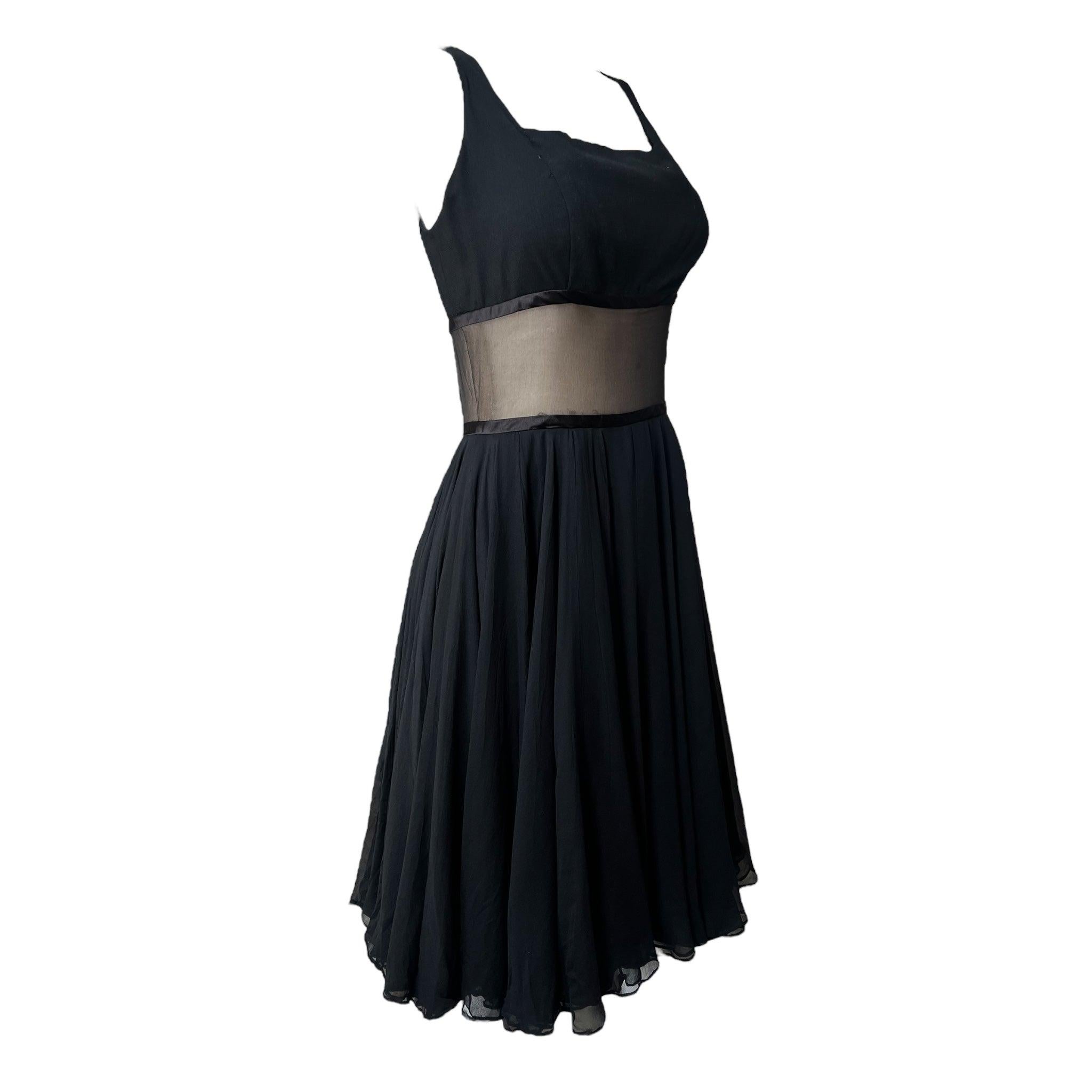 A classic 1960's A-line silhouette little black cocktail dress. The silhouette features wide shoulder straps, a fitted bodice with a sheer chiffon panel at the waist, and a full flowing skirt with three layers. Lined bodice and skirt. Side zip