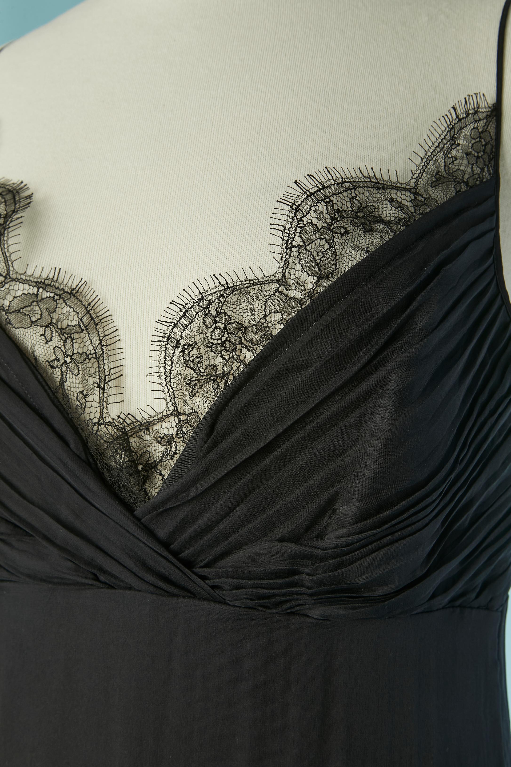 Robe de soirée en mousseline de soie noire avec traîne et bord en dentelle. Fermeture zippée et crochet sur le côté gauche. 
Plissé sur le buste. Doublure en rayonne noire à l'intérieur du buste et doublure en jersey de polyester noir. 
Longueur