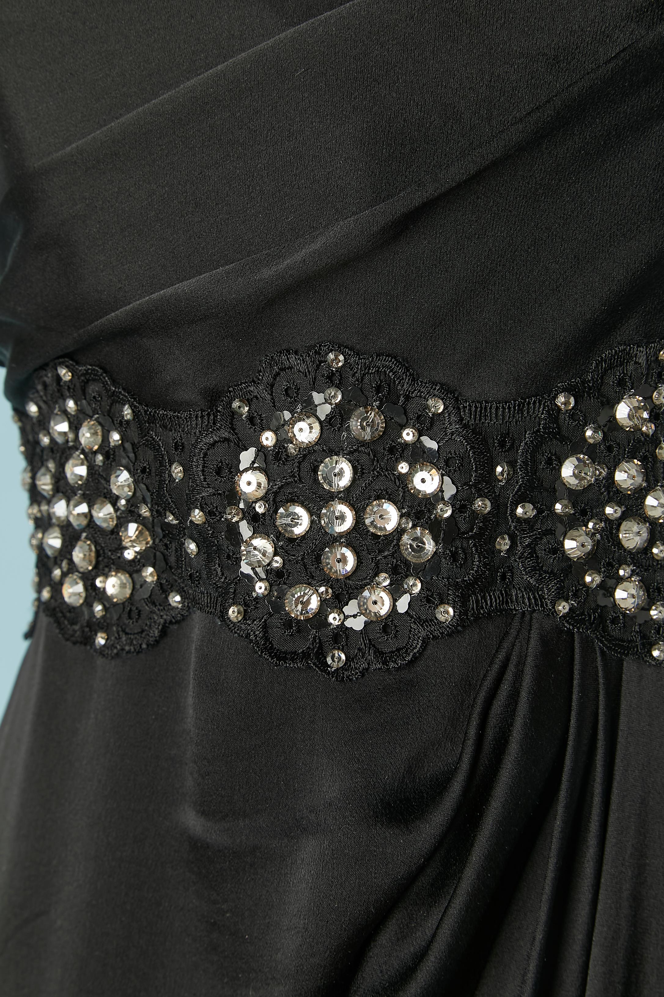 Abito da sera in seta nera con fascia in vita in pizzo e strass. Busto drappeggiato. Avvolgi la parte della gonna con dei volant. Chiusura con zip e gancio al centro della schiena. Disossato sul busto. 
Lunghezza totale davanti = 150 cm
Lunghezza