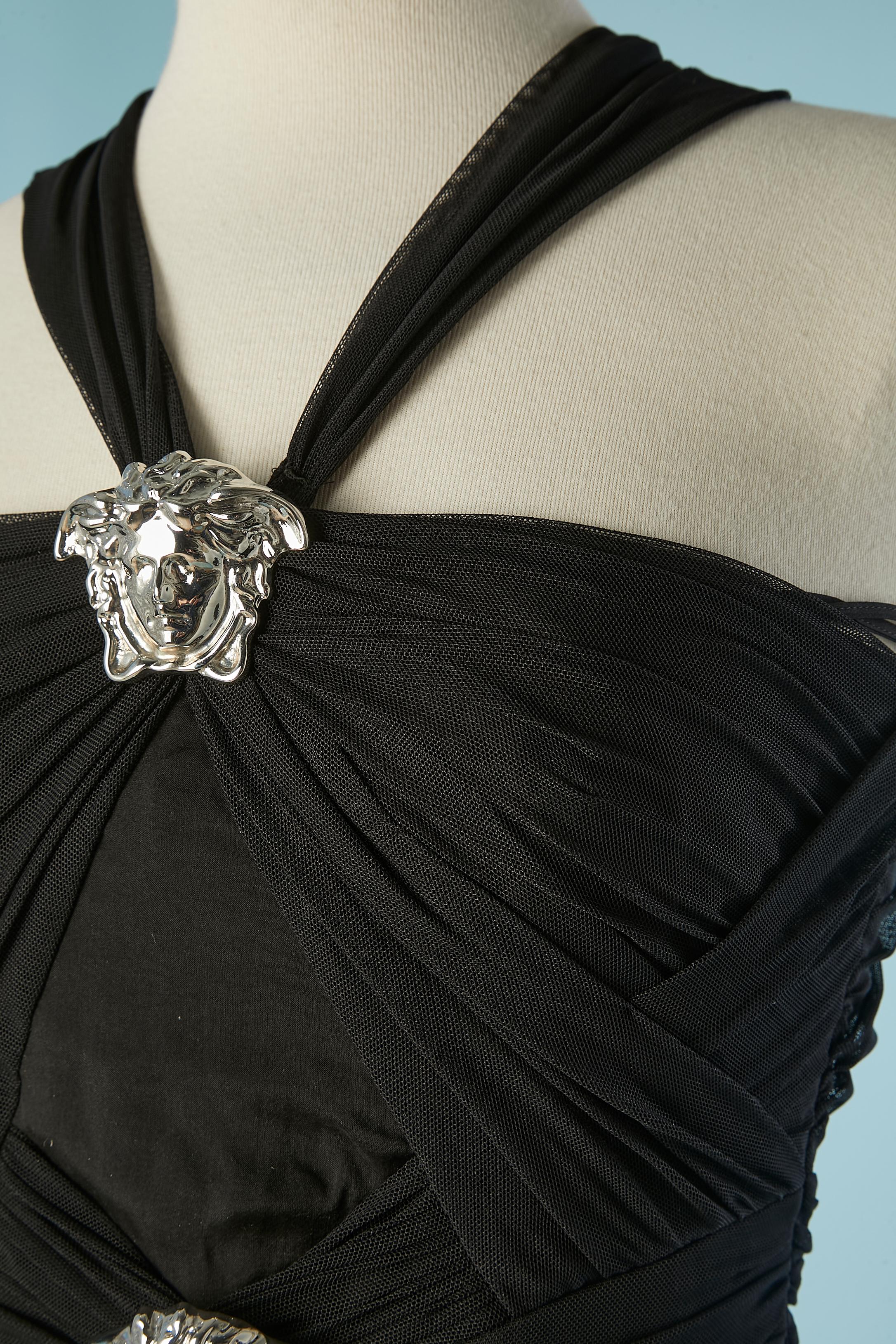 Black silk evening dress with silver metal Medusa. Boned. Zip on the left side with branded zip-puller. Draped on the bust. Snap in the middle front on the bust to attach the shoulder strap. Gros-grain waist band. Fabric composition: Top fabric: