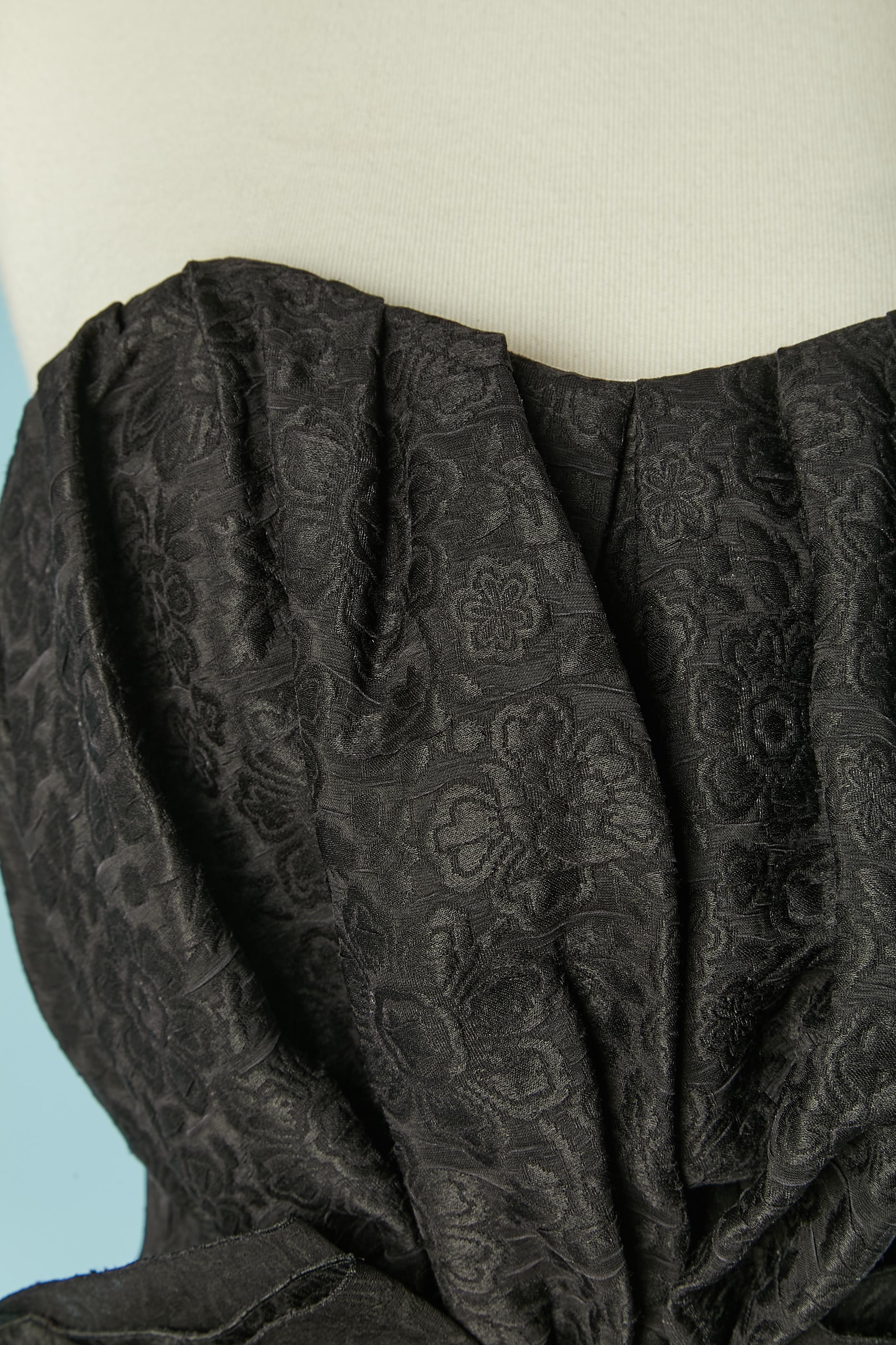 Abito da cocktail con bustier a palloncino in seta jacquard con bustier disossato all'interno e reggiseno con ferretto. Fiocco al centro della vita e volant. Fodera: 70% poliestere, 30% seta. 
Tubi in gros grain all'interno. Cintura in gros grain