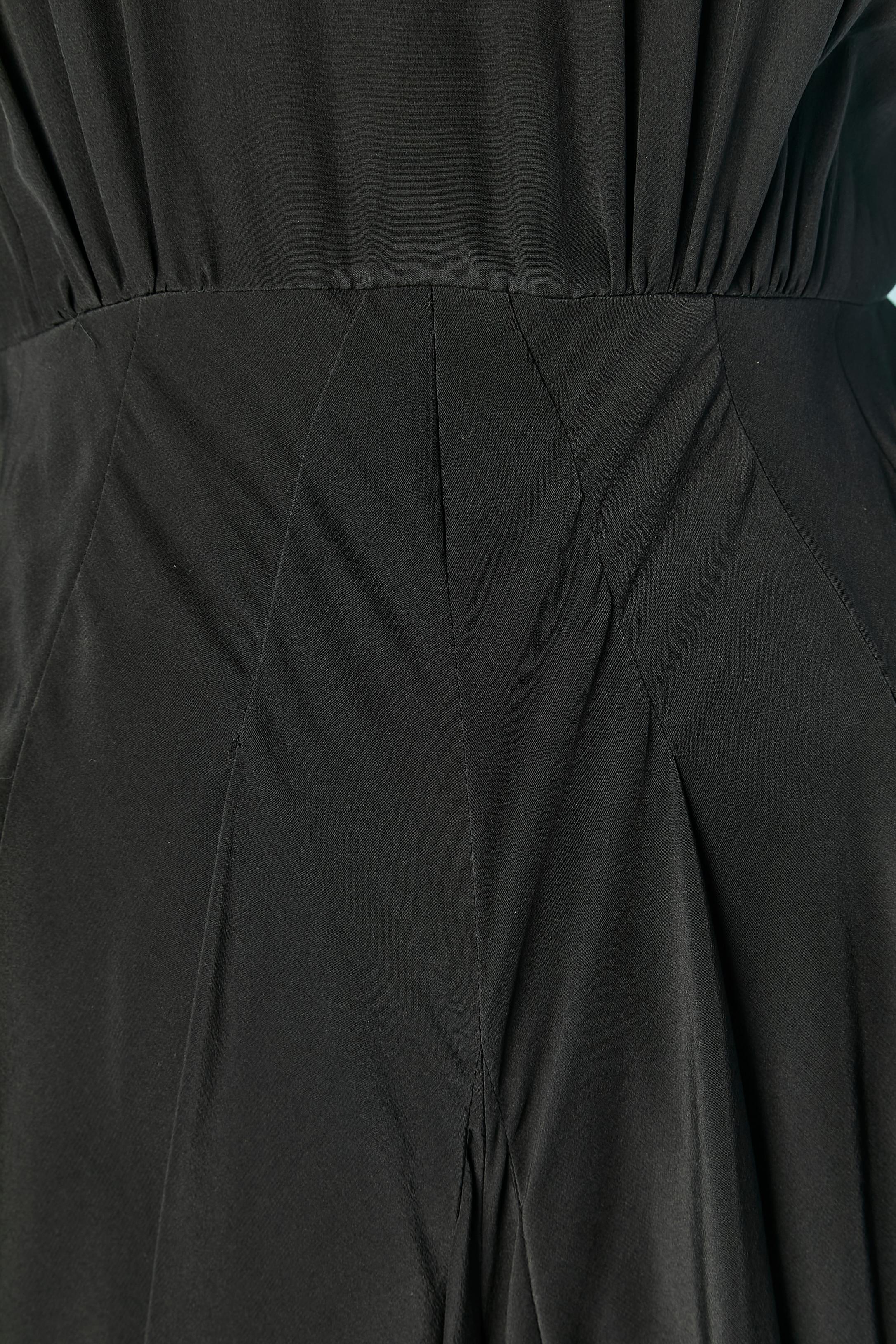 Black silk jumpsuit with cut-work. Larges Shoulder pad. Zip closure in the middle back. Draped on the side on the hips with small weight inside to keep the drape. One Button and buttonhole on the cuffs. 
SIZE 4 (US) XS 