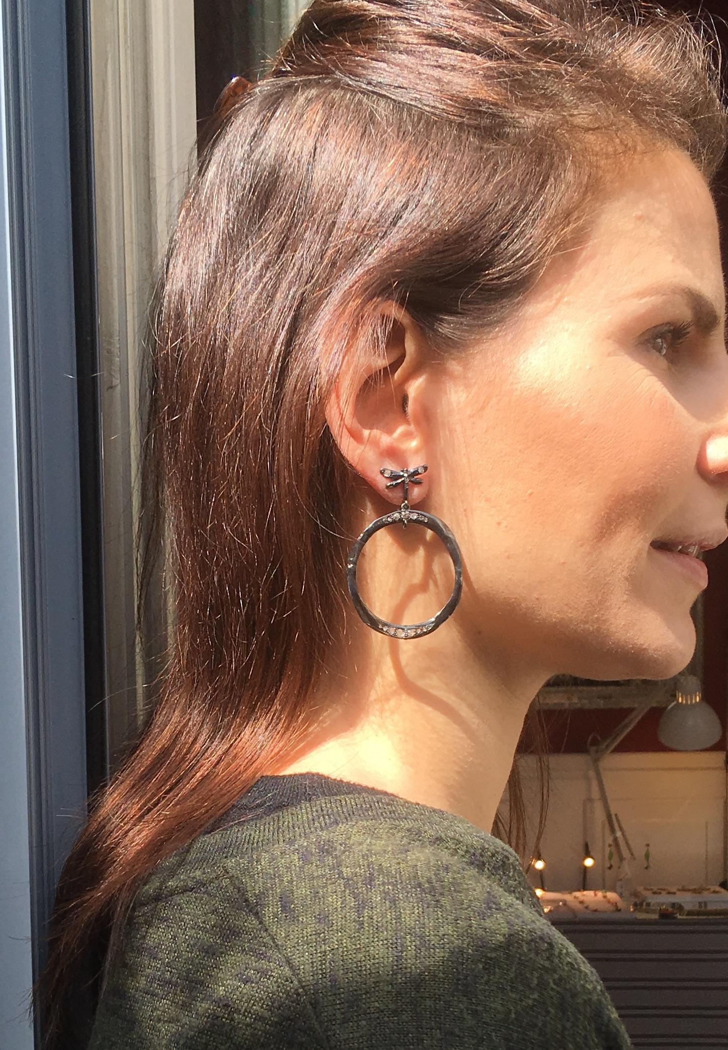 Introducing Rossella Ugolini's Elegant Circular Burnished Silver Earrings adorned with 0.70 Karat Antique Old Mine and Old Cut Diamonds, each featuring a delicate symbol of freedom—the dragonfly. Crafted to perfection, these One-of-a-kind hoop