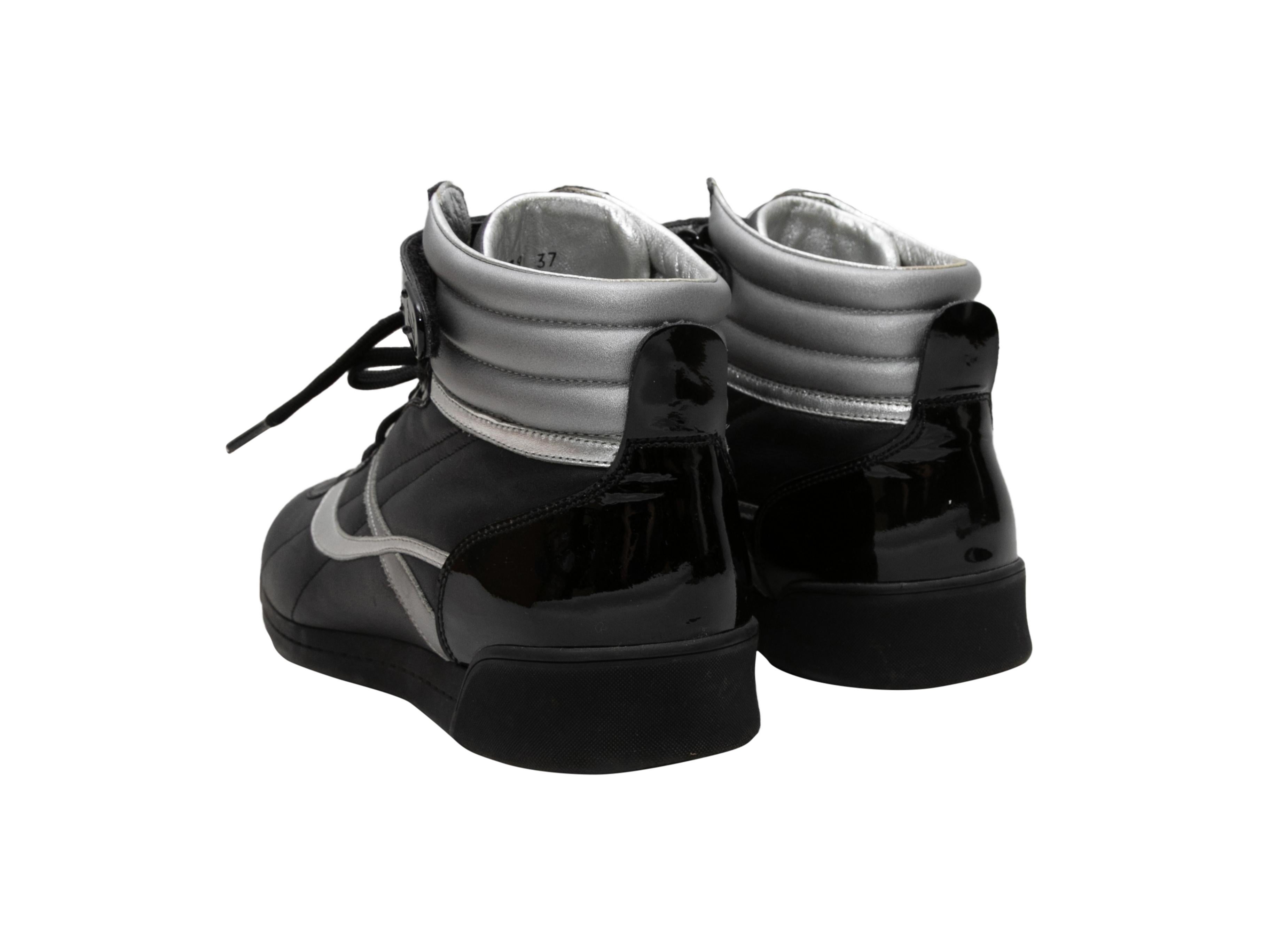 Black and silver leather high-top sneakers by Louis Vuitton. Rubber soles. Lace-up tie closures and velcro straps at tops. 4.5