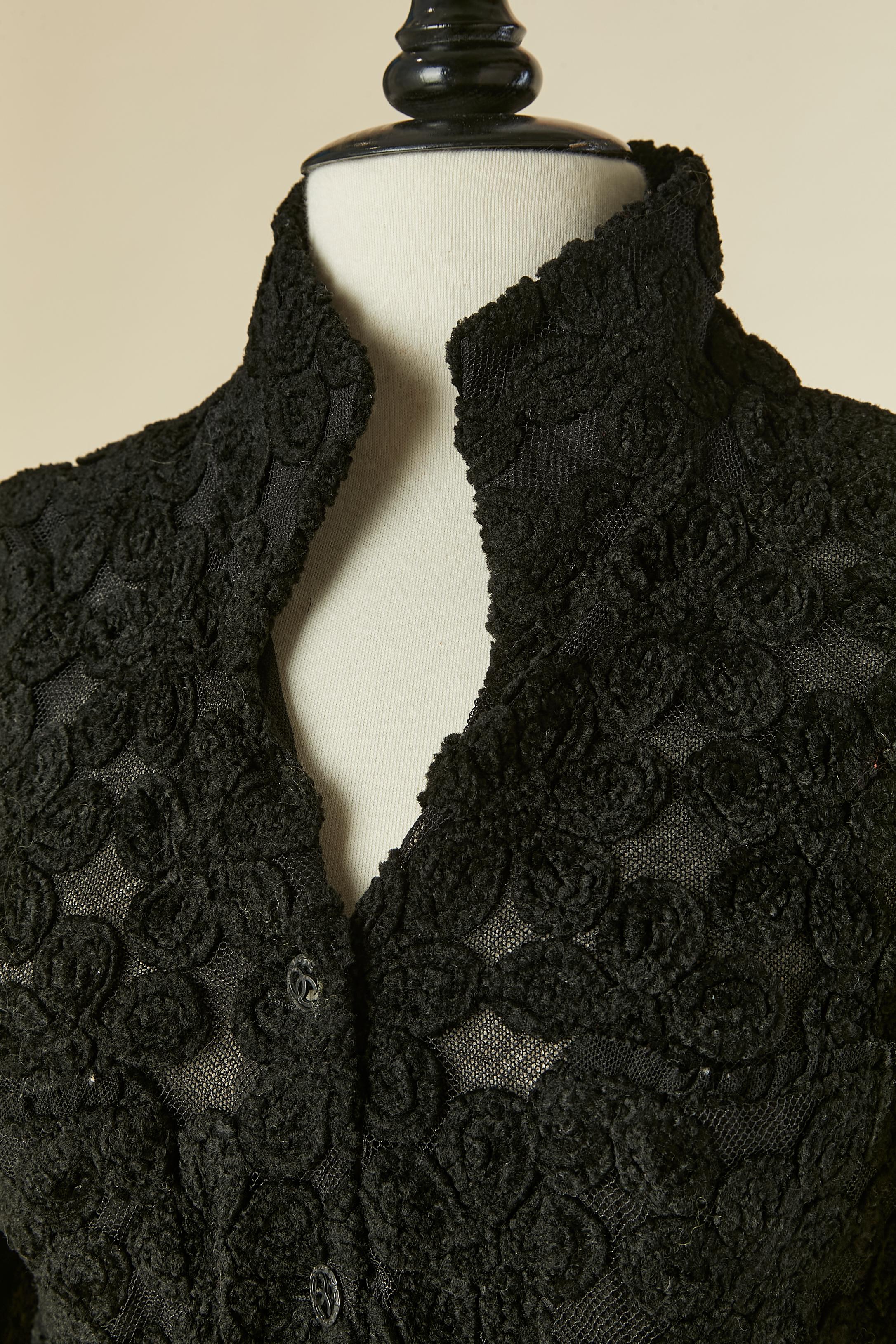 Manteau noir à simple boutonnage avec application de fleurs en velours sur tulle. Transparent des hanches jusqu'au bas. Composition du tissu principal : 33% acrylique, 26% laine, 11% soie, 5% coton. Doublure en tulle. 
Bouton et boutonnière marqués