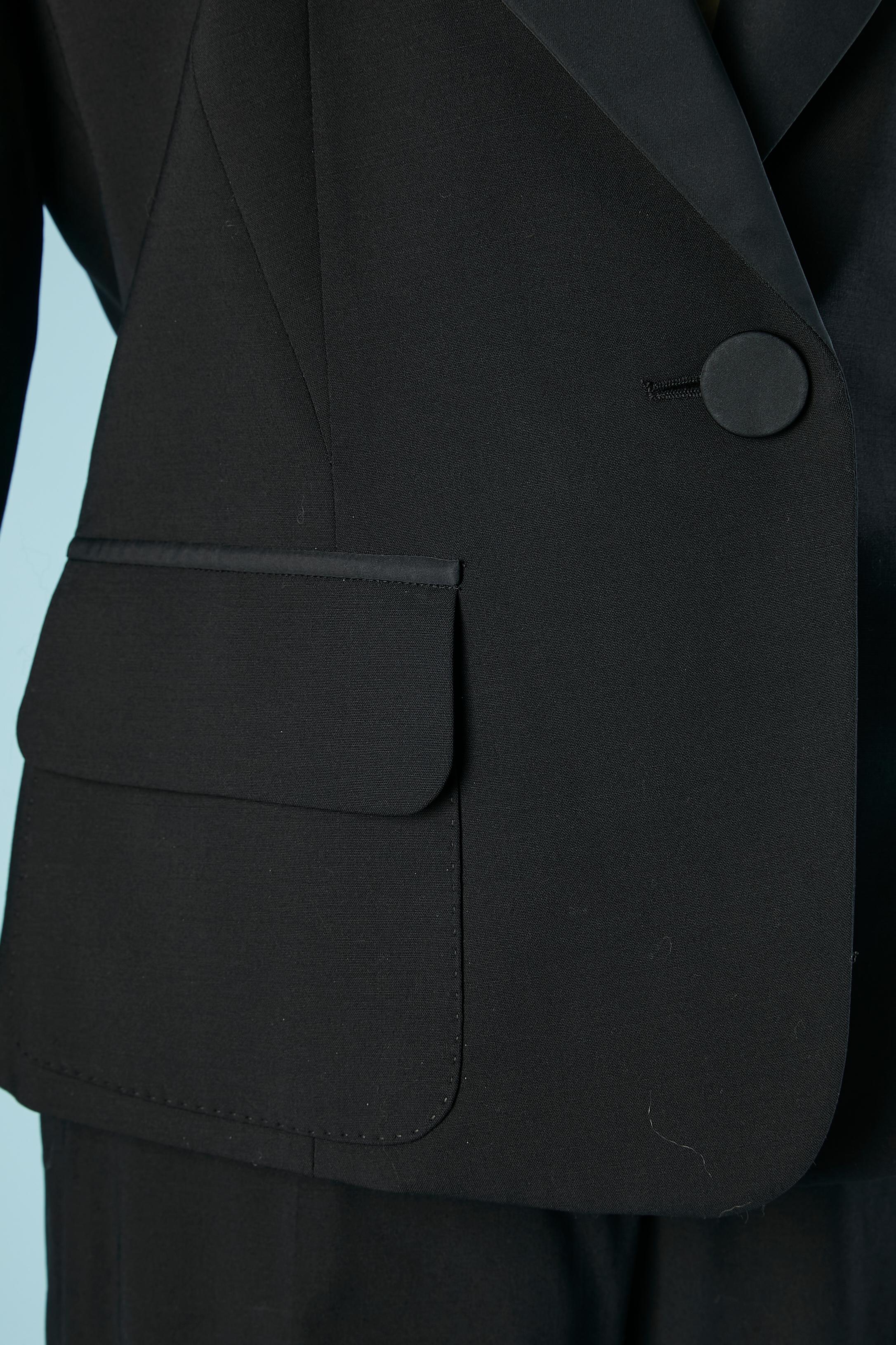Black single-breasted tuxedo with ruffle on the cuff . Shoulder-pads. Fabric buttons. Top-stitched pockets. Branded silk lining. Fabric composition: 74% wool, 16% polyamide, 7% silk, 3% stretch. Buttons and buttonhole on the bottom side of the
