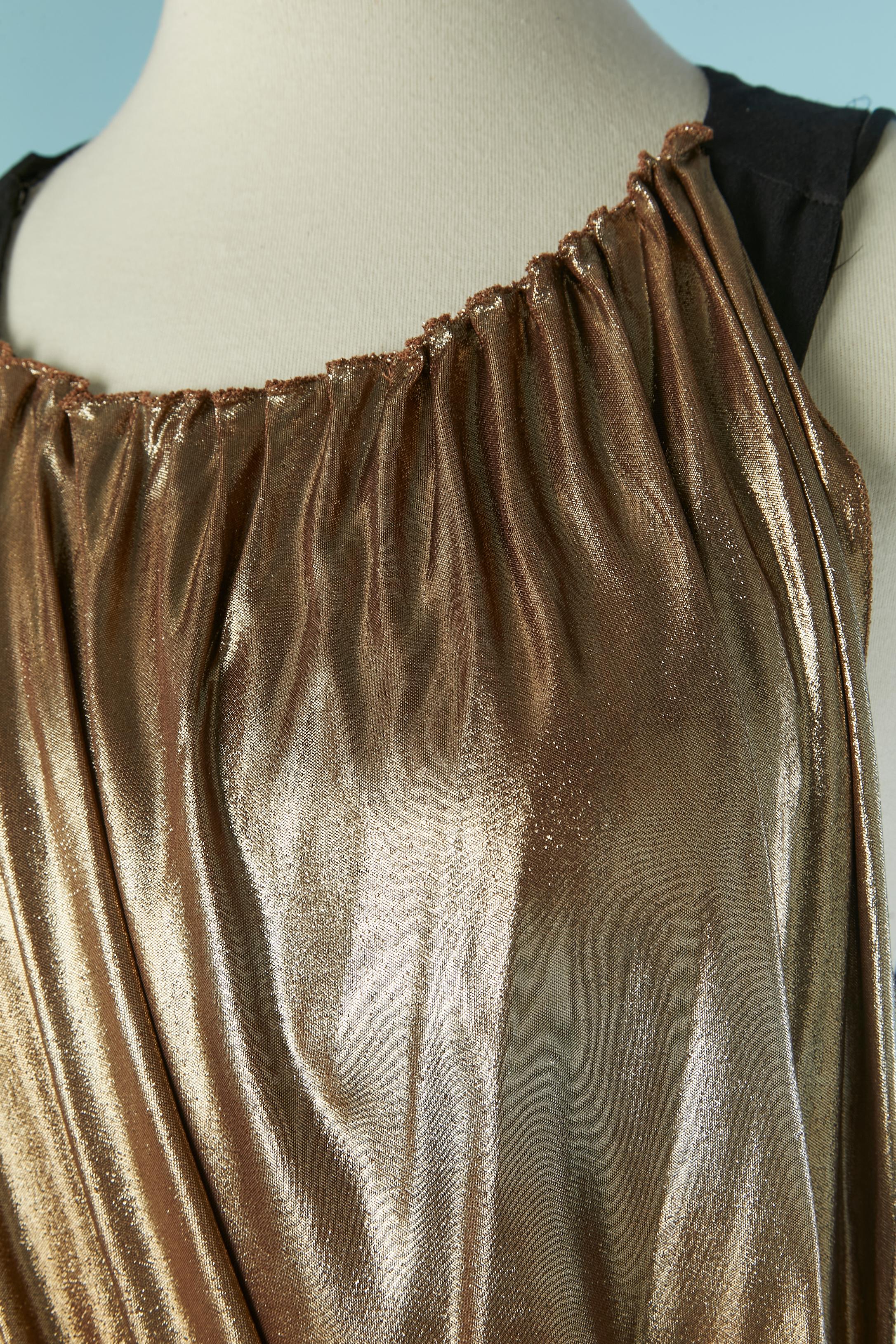 Schwarzes, ärmelloses Cocktailkleid aus Viskose mit goldfarbenem, drapiertem Jersey am Oberteil. Das schwarze Kleid ist mit Bügeln versehen und hat einen Bügel-BH. Elastisches Unterbrustband. Haken und Öse oben rechts auf dem schwarzen Kleid.